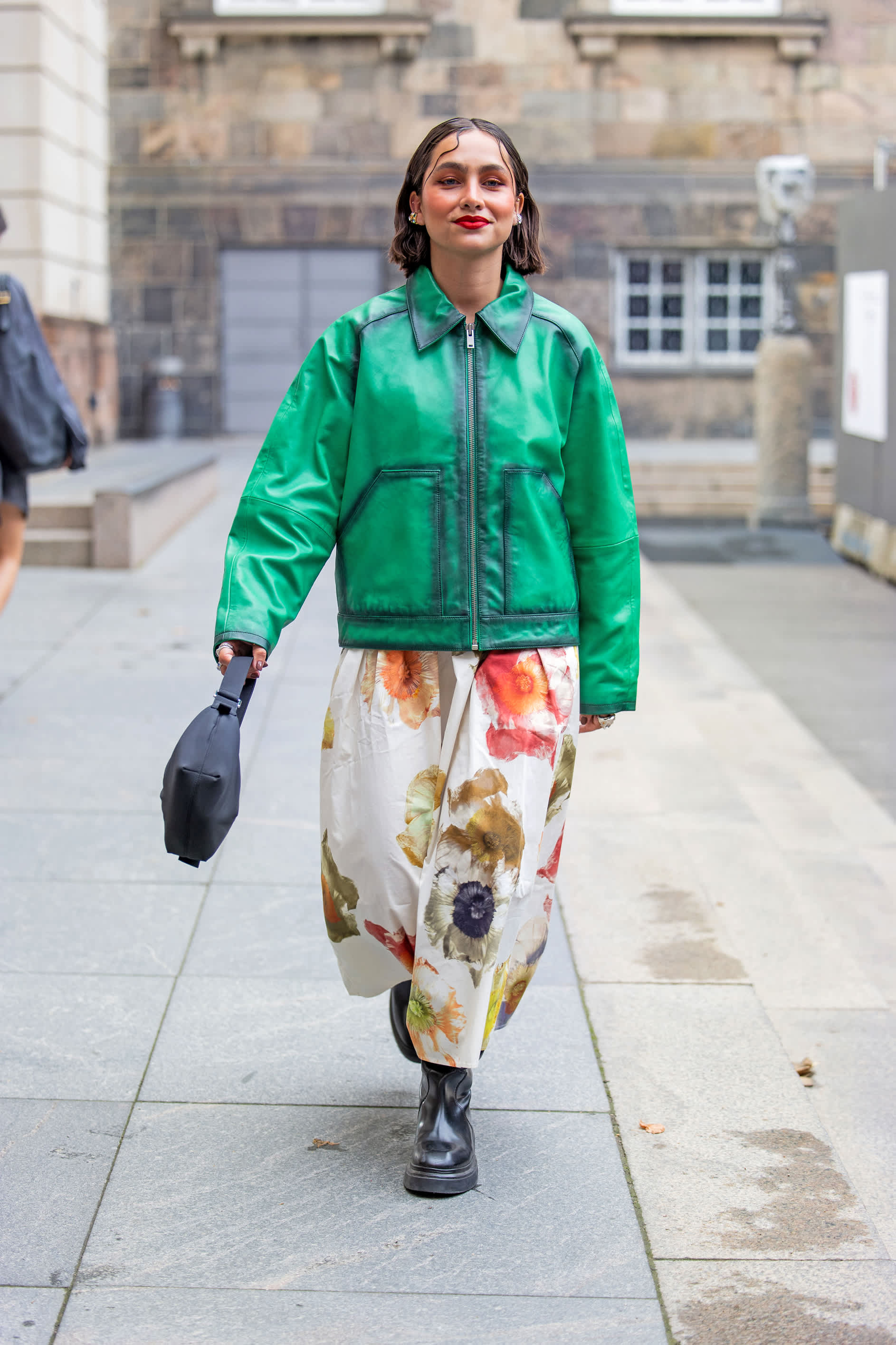 Frau trägt grüne Lederjacke und weißen Rock mit Blumenmuster in Kombination mit schwarzen Combat-Boots auf Straße in Copenhagen.