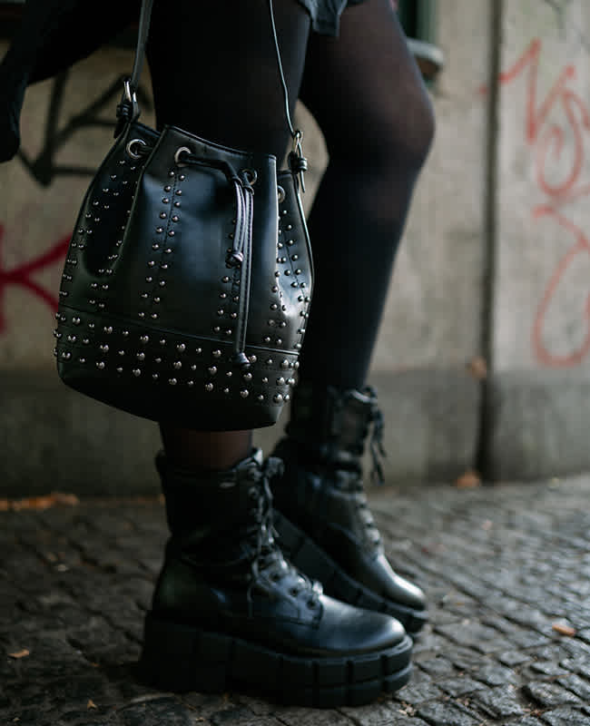Nahaufnahme einer Person mit Buffalo Plateau-Boots, schwarzer Strumpfhose und schwarzer Nietentasche