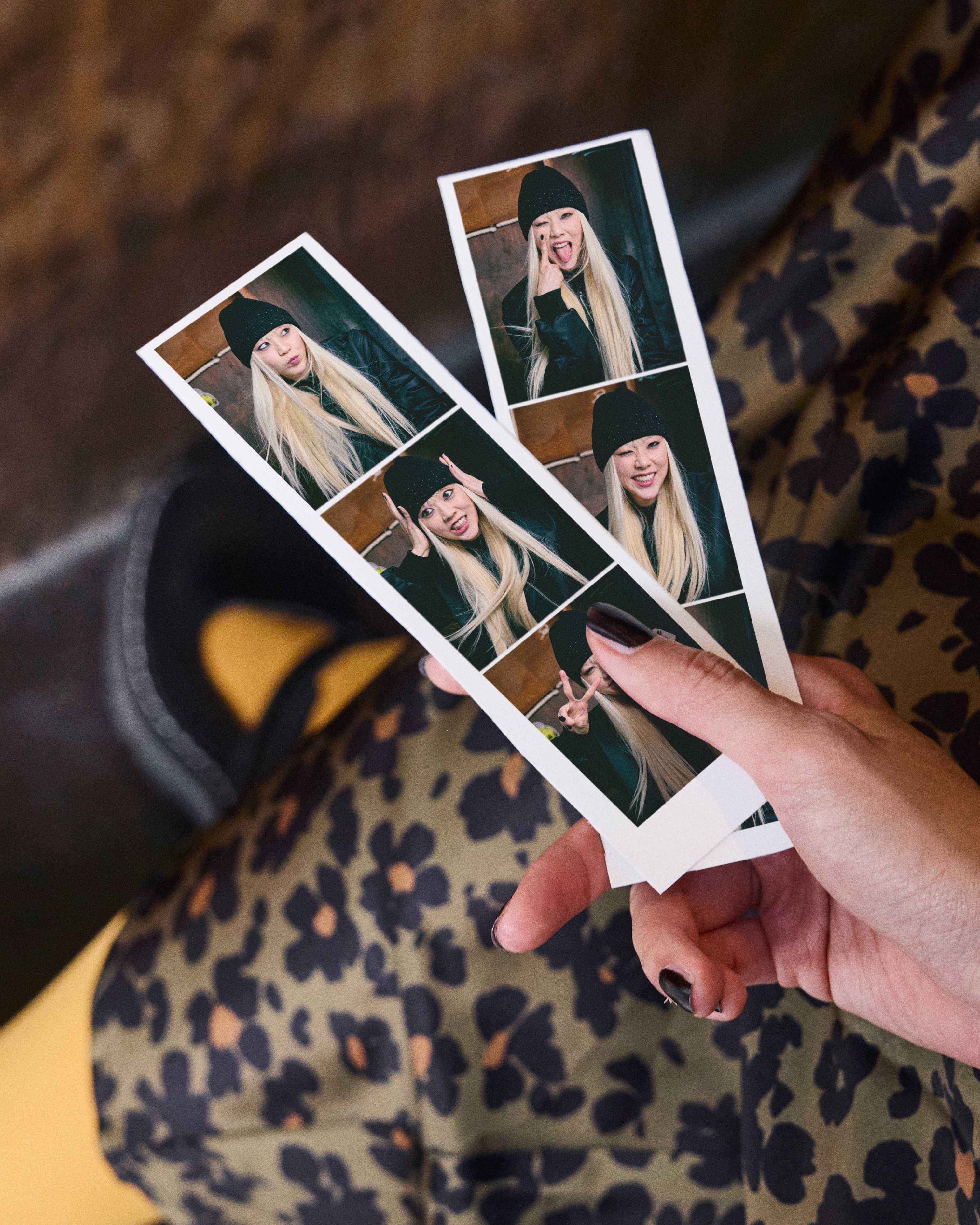 Person hält zwei Fotostreifen, auf denen eine blonde Frau abgebildet ist, die Grimassen schneidet. Outfit mit Leopard-Muster im Hintergrund