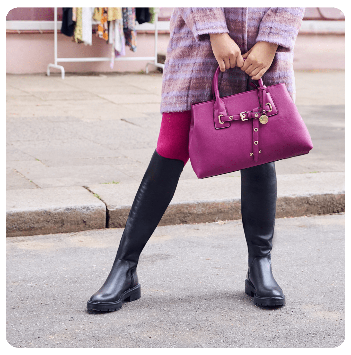Frau in schwarzen Underknee-Boots, kombiniert mit pinker Hose, rosa Jacke und Shopper-Bag in Pink