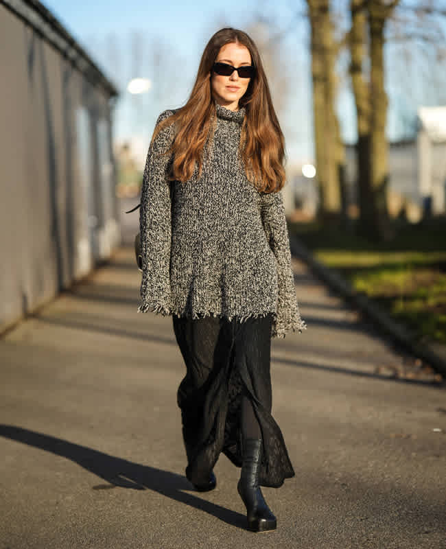Frau mit kniehohen Biker Boots in Kombination mit Slip-Dress und Oversize-Pullover