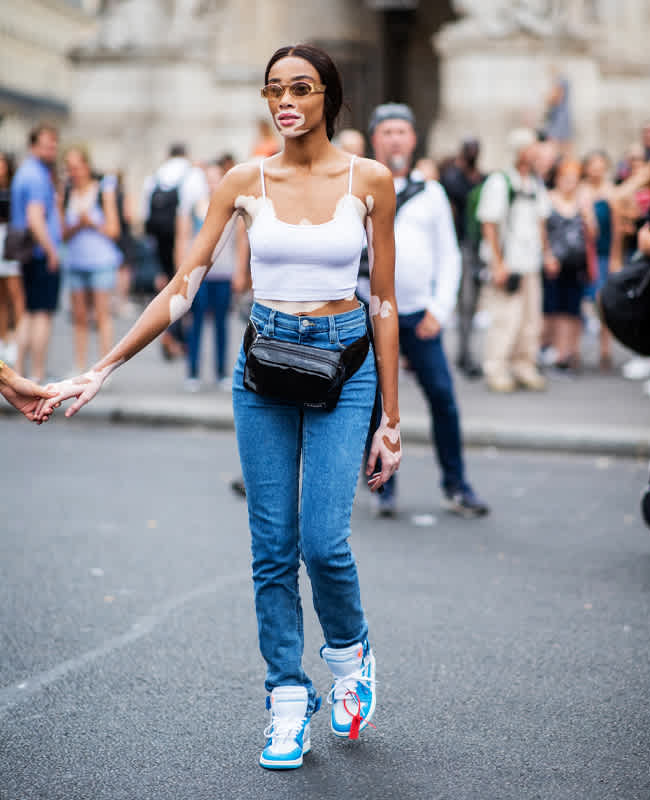 Frau auf Straße mit weißem Top, Denim Jeans und schwarzer Bauchtasche