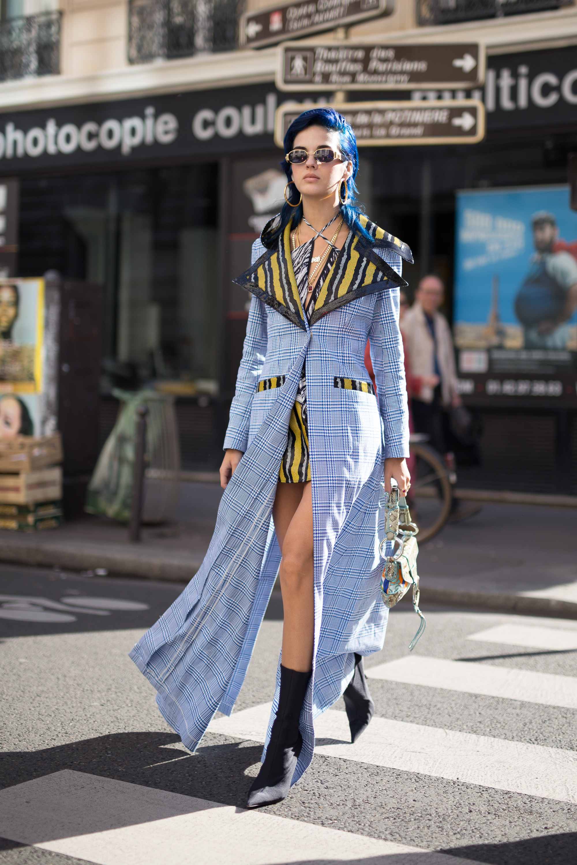 Frau mit bodenlangem Kleid in Blau und Sonnenbrille läuft über Zebrastreifen