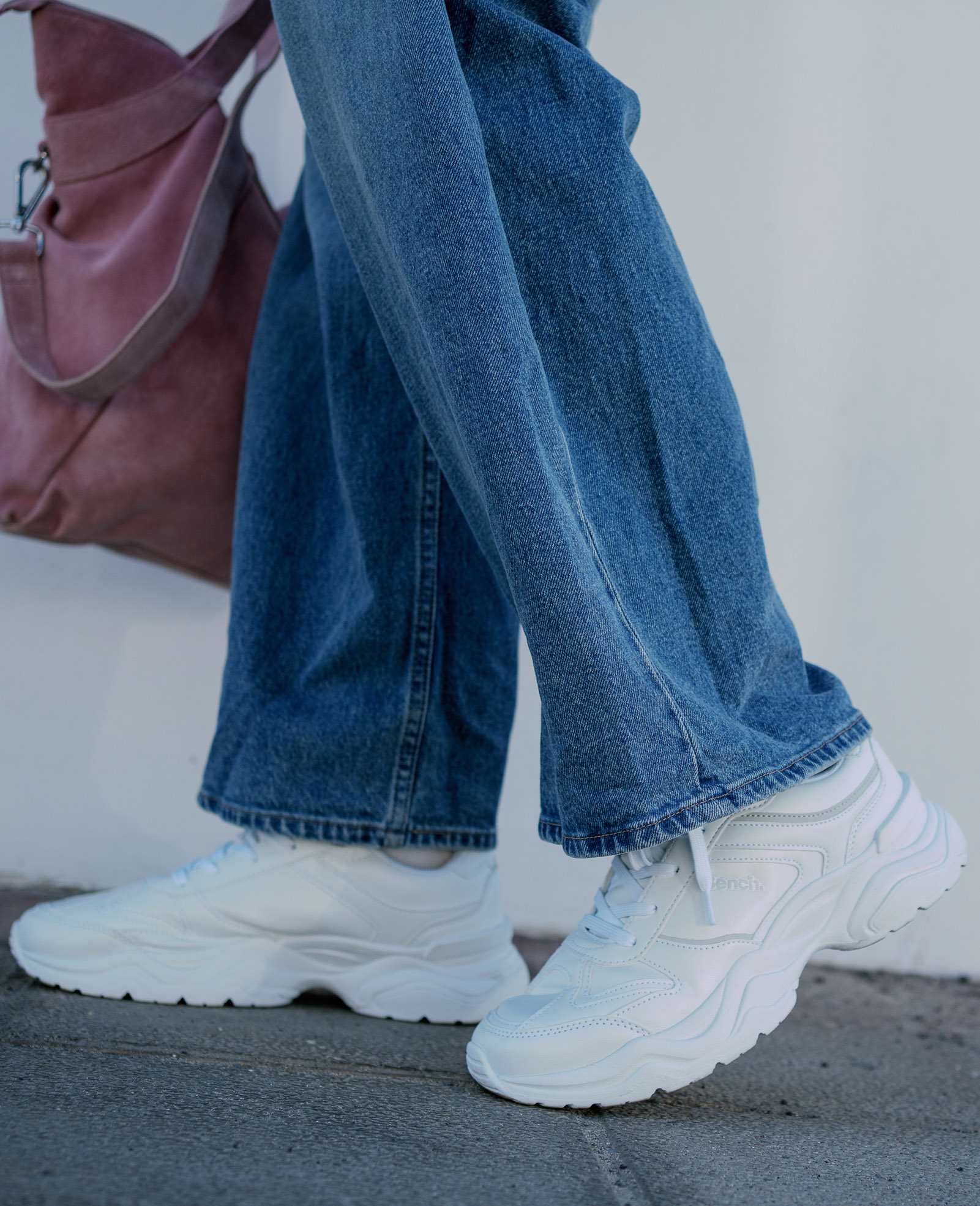 Nahaufnahme einer Frau mit weißen Sneakern und Jeanshose