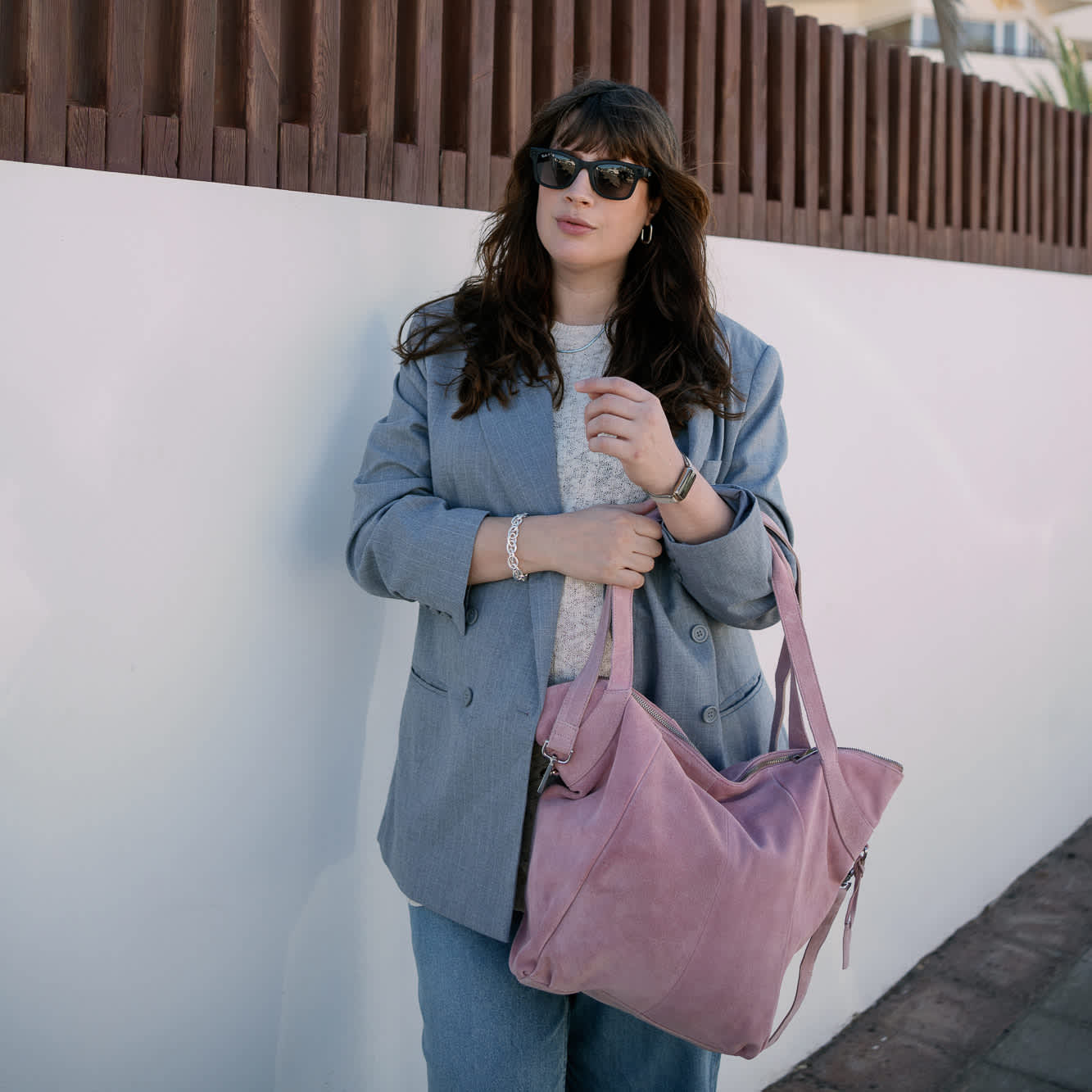 Schwangere Frau in Jeans-Outfit und rosa Handtasche