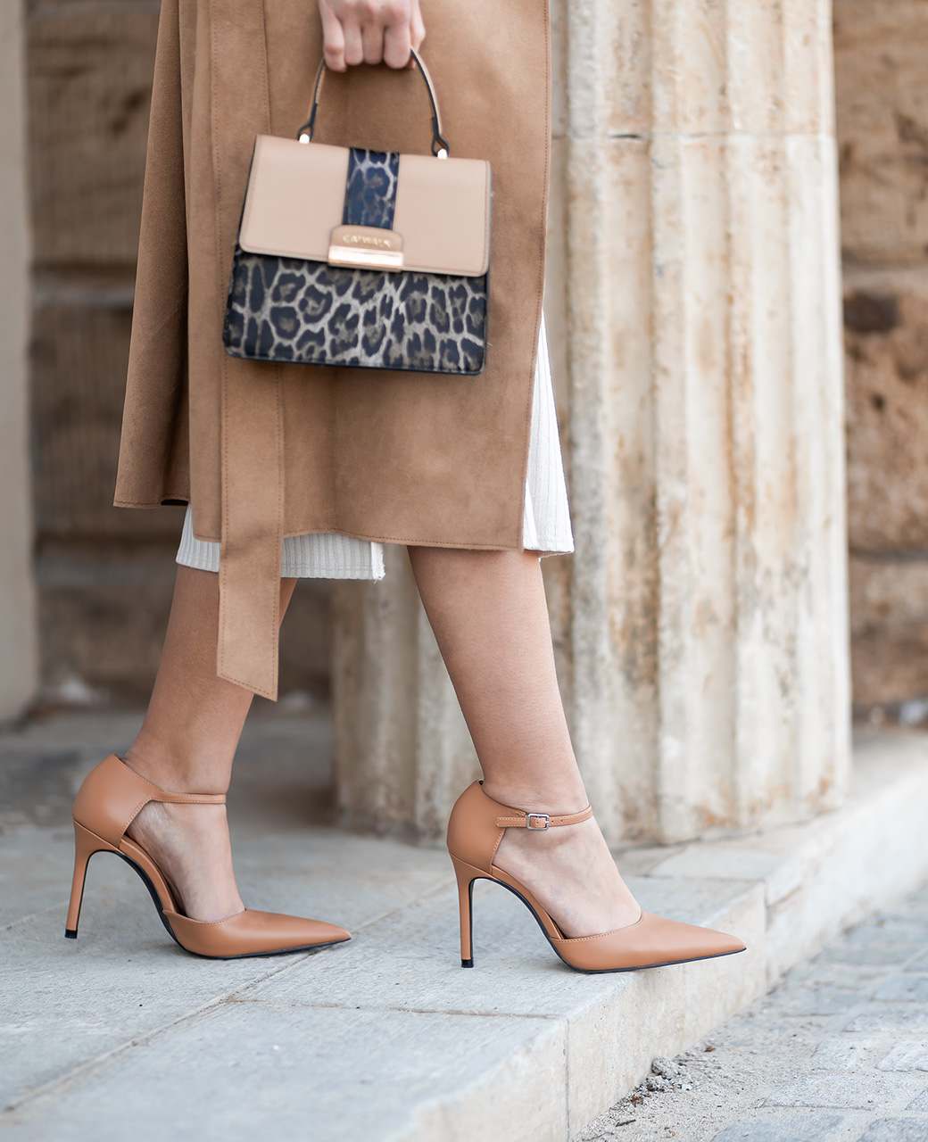 Close-Up einer Frau mit braunen High Heels zum passenden leichten Mantel, mit Leo-Handtasche am Arm