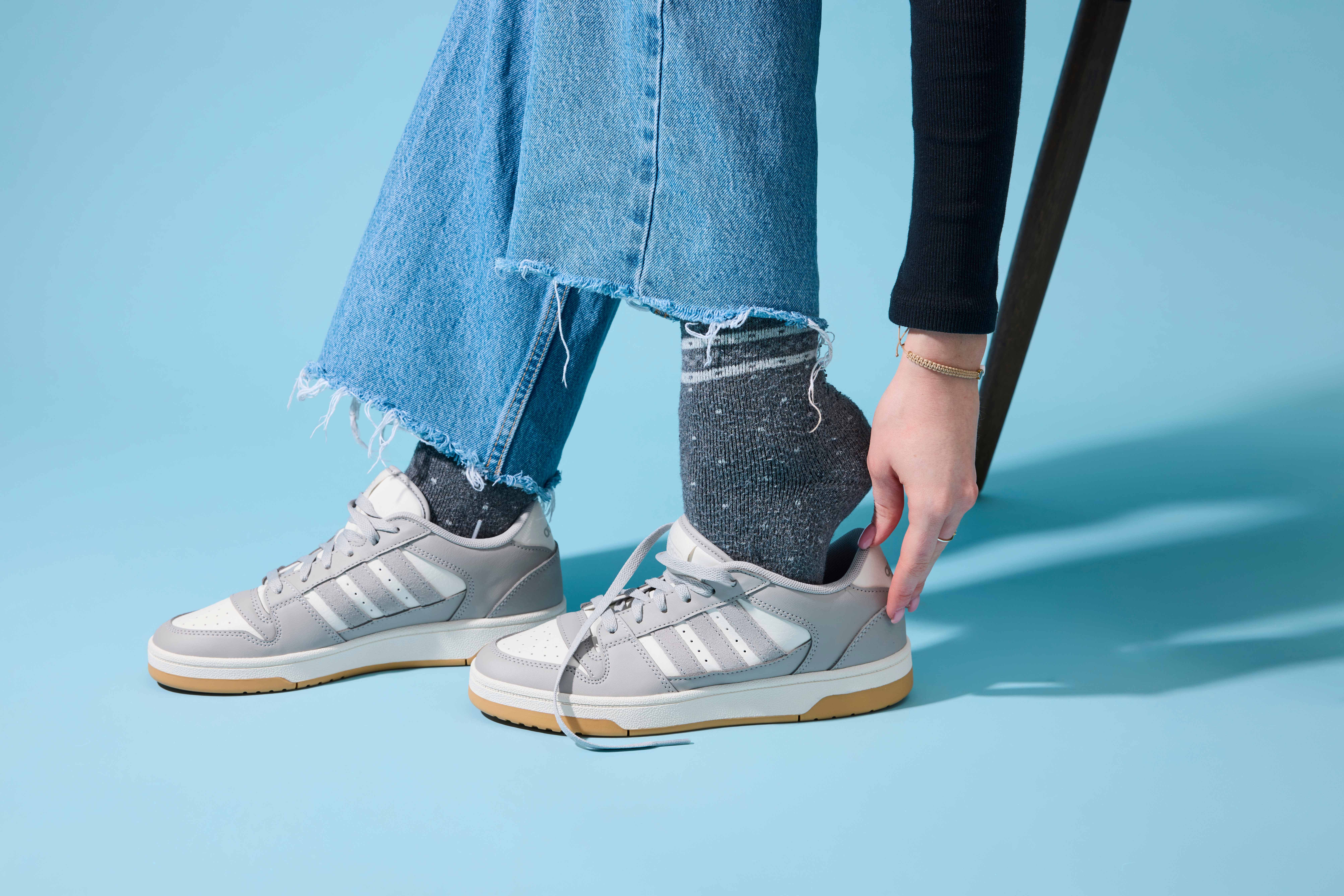 Frau schlüpft mit dicken Socken in enge Schuhe, um diese zu weiten