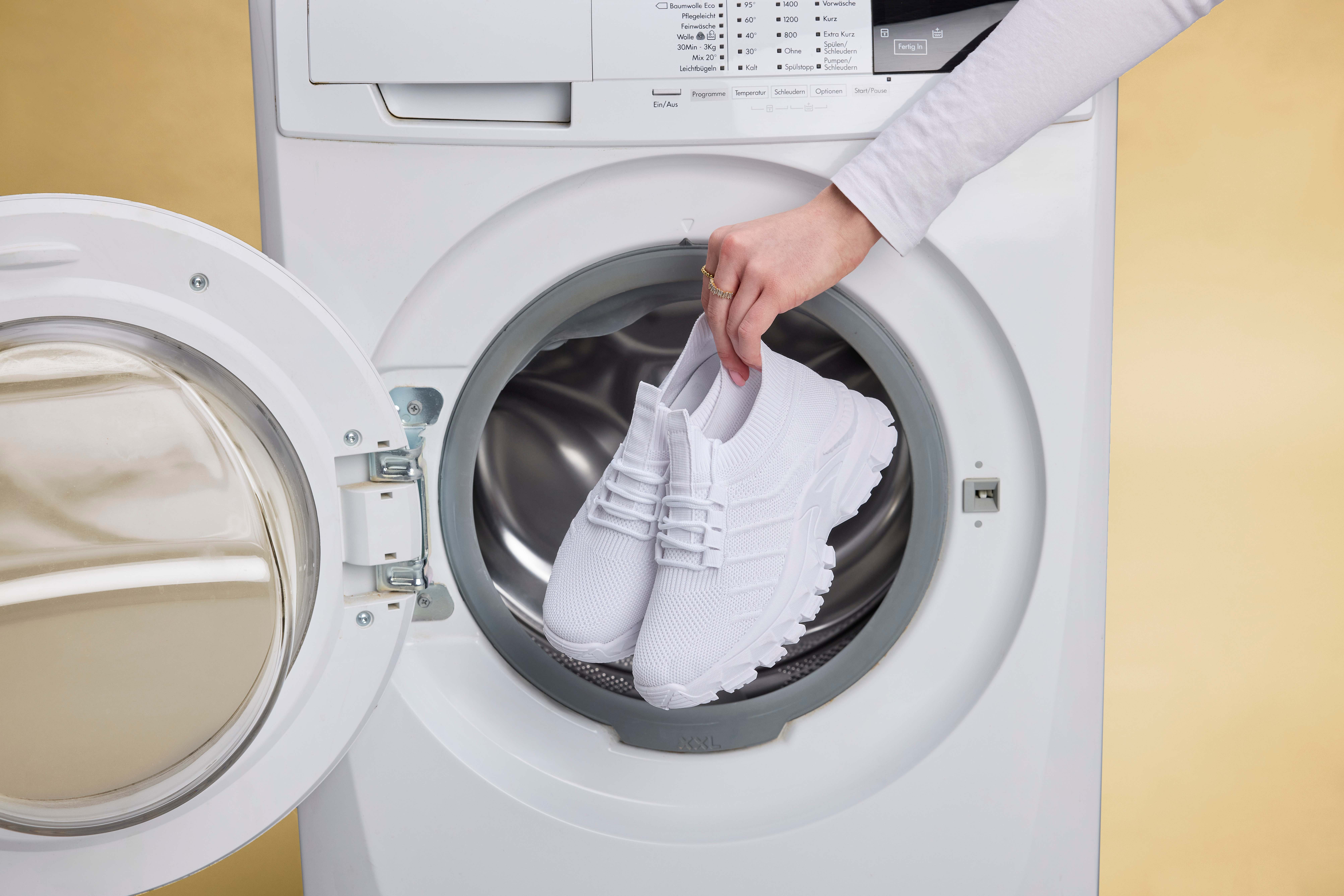 Person platziert Schuhe in Waschmaschine für Wäsche