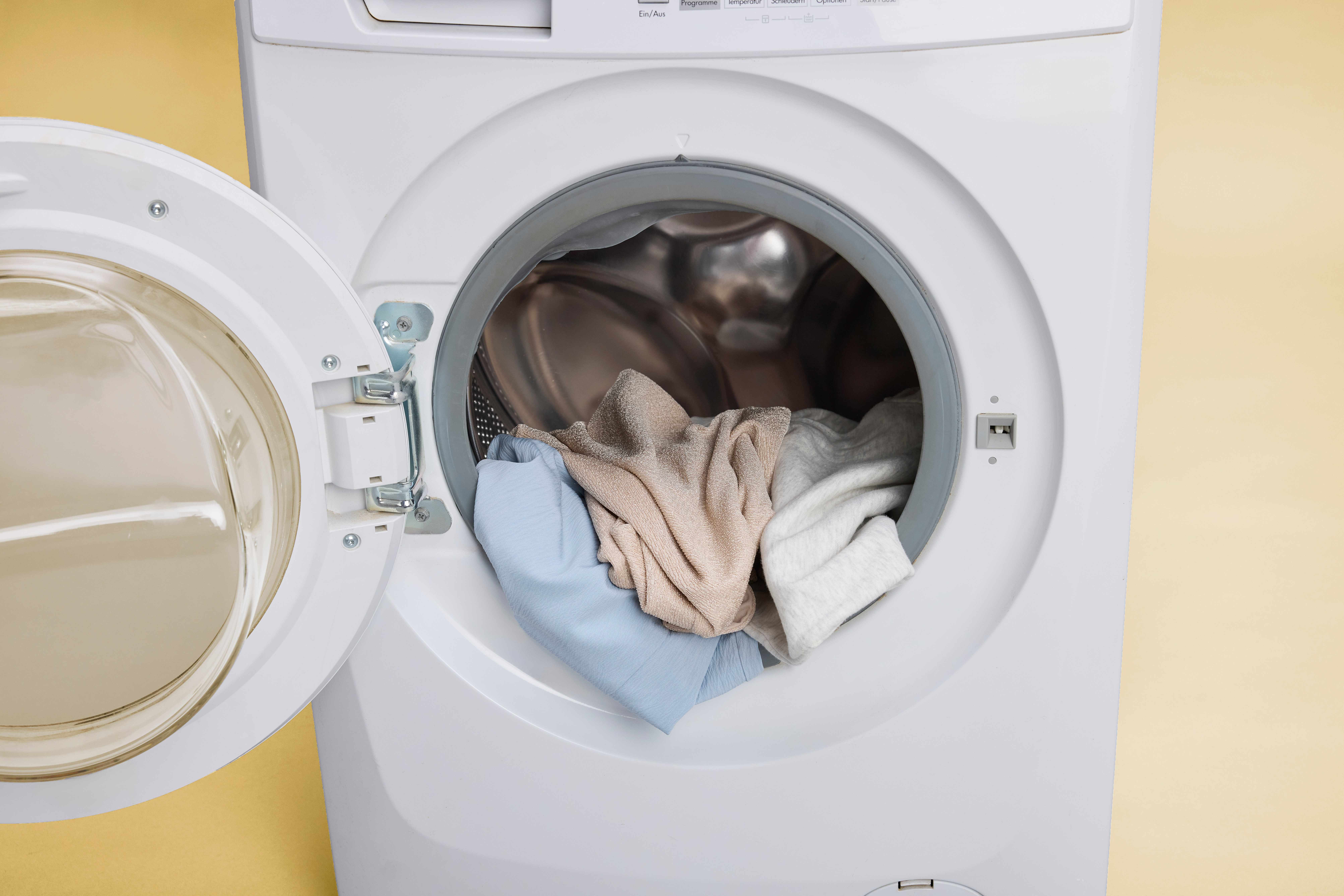 Kleidungsstücke mit Kaffeeflecken liegen in Waschmaschine