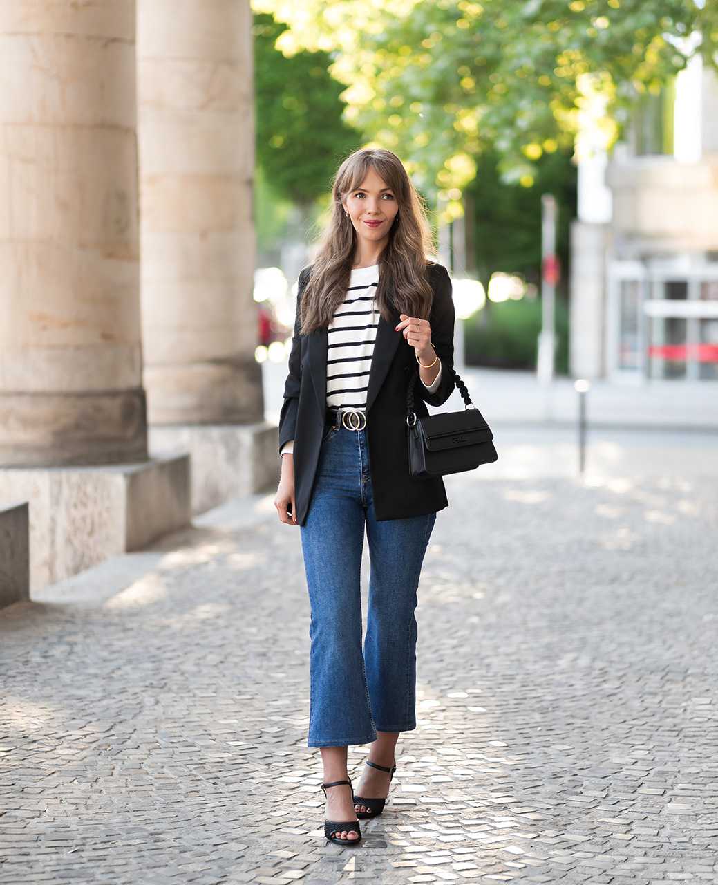 Frau beim Spaziergang im Casual French Look mit oversize Blazer, Jeans und transparenten Schuhen