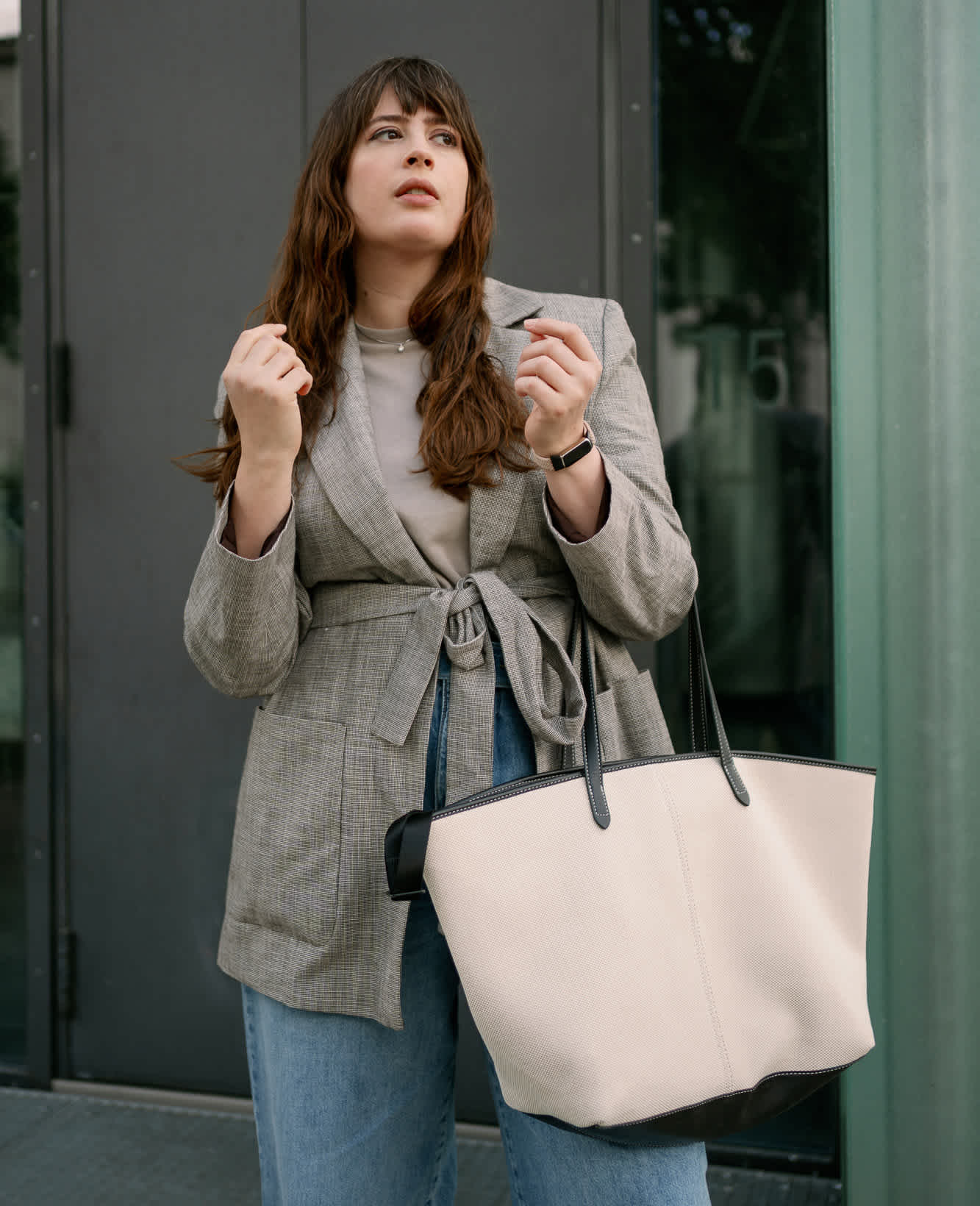 Frau mit grauem Blazer und beigefarbener Shopping-Bag