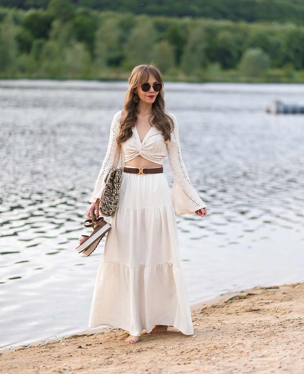 Frau in weißem Outfit im Boho-Look, steht am Strand