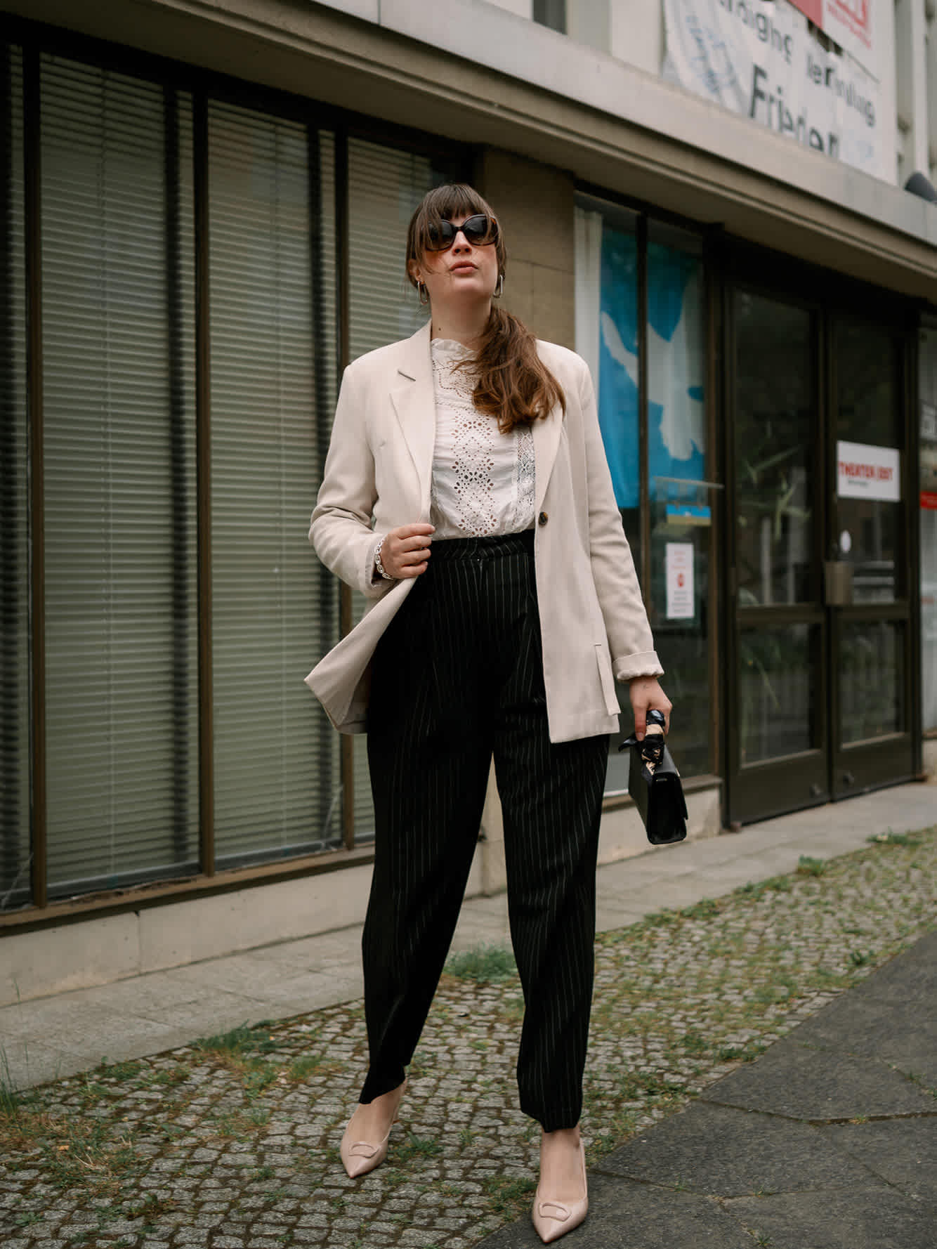 Frau in weißem Business-Outfit mit Slingback-Pumps in urbaner Umgebung