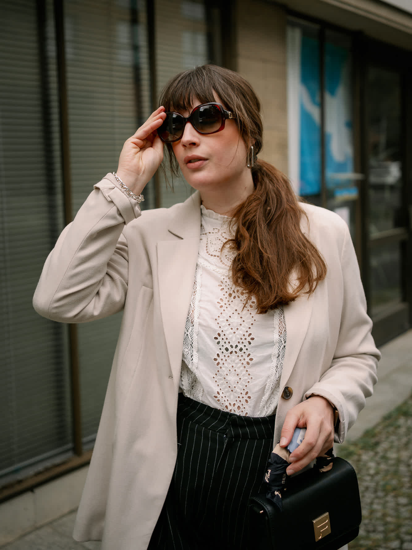 Frau in Business-Dress mit beigem Blazer, weißem Oberteil und schwarzer Hose