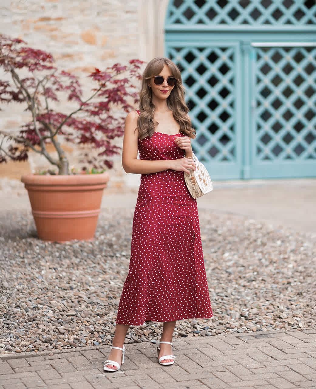 Frau in weißem Kleid mit roten Punkten, trägt beige Shopper-Tasche unterm Arm