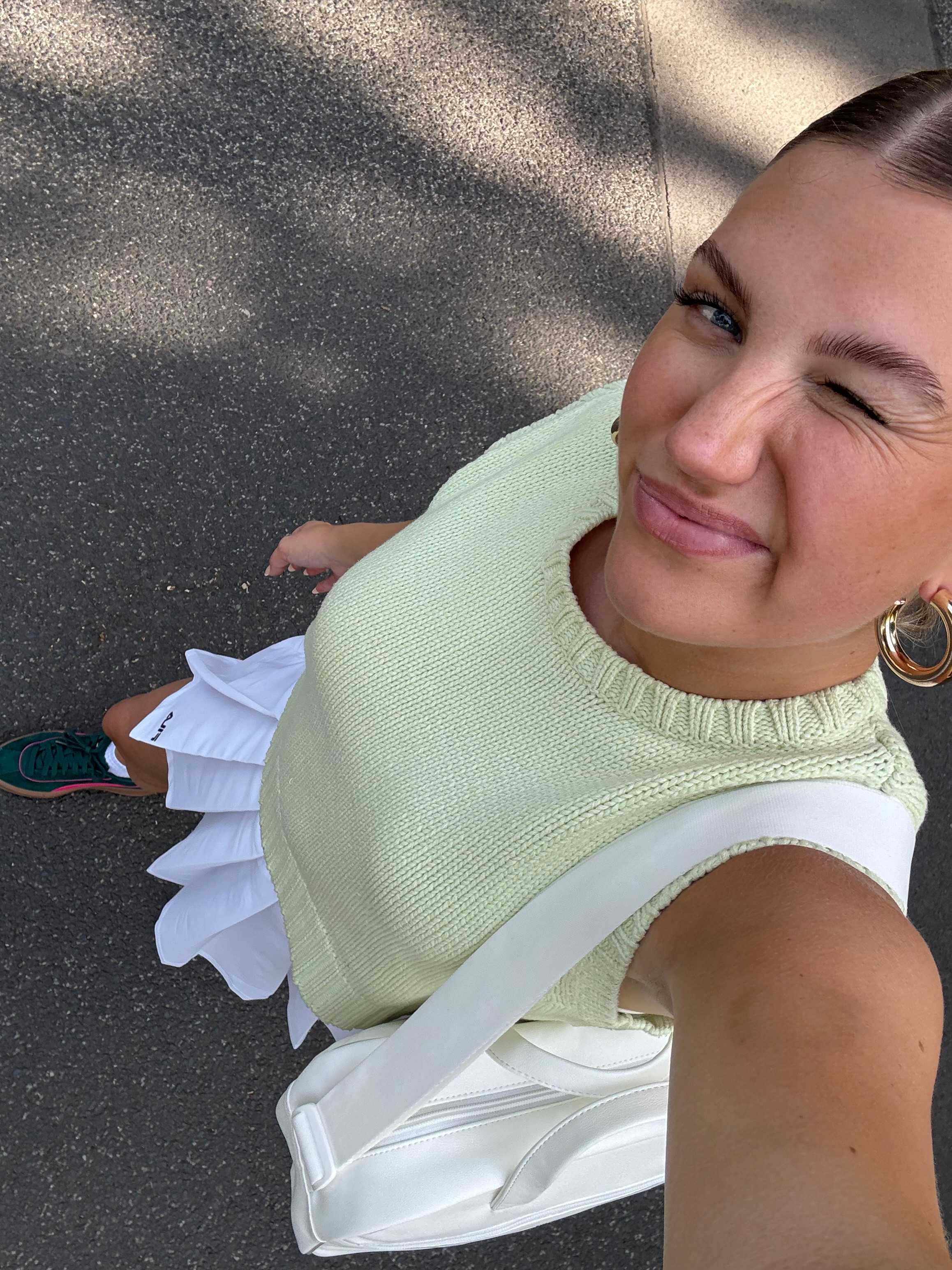 Frau in gelb-weißem Tennis-Outfit zwinkert in Kamera