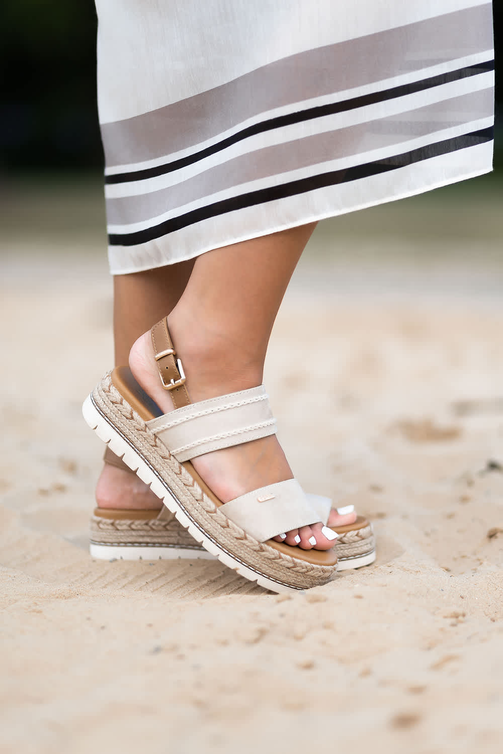 Frau in weißen ESPRIT-Sandalen steht auf Sandstrand