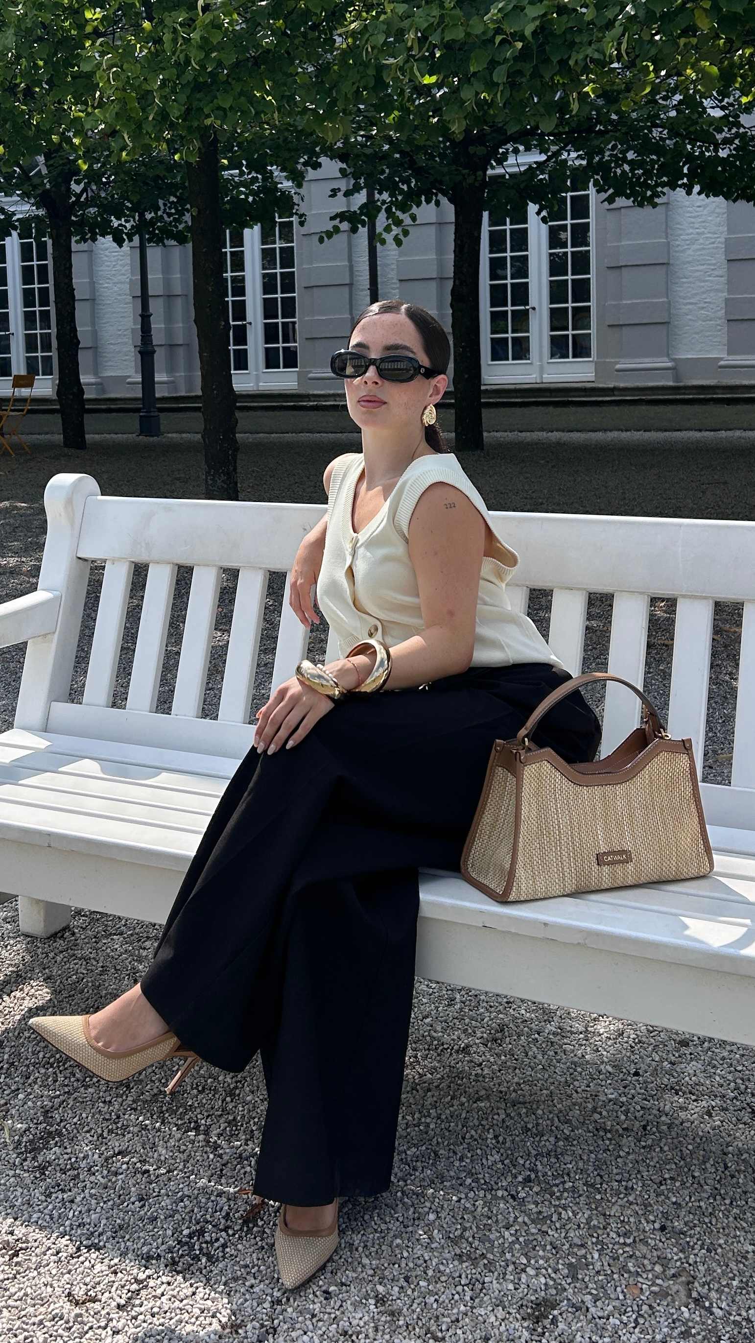 Frau sitzt auf einer Bank und präsentiert casual ihr Outfit im Old Money Style