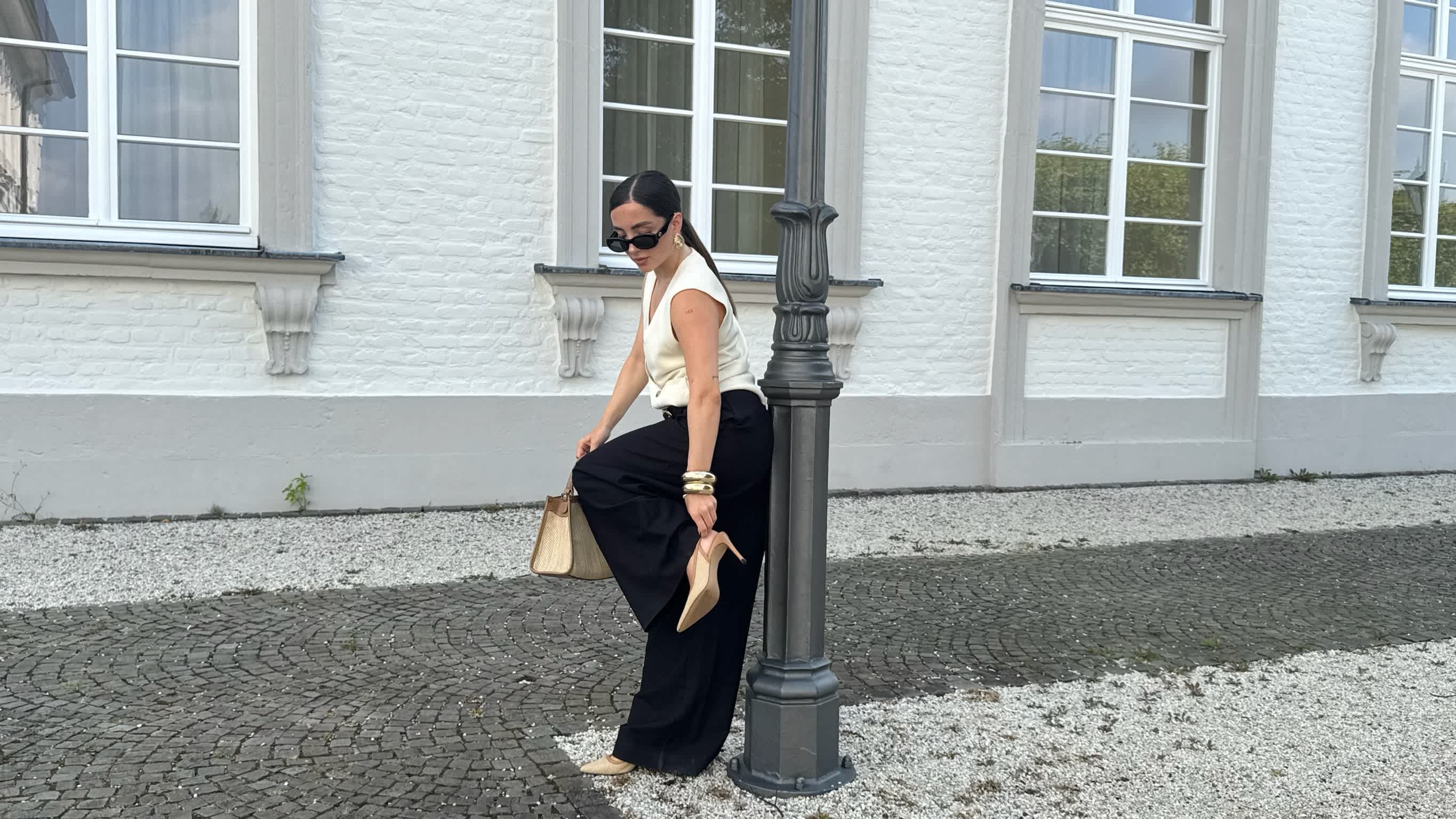 Frau zeigt die Sandaletten, die zu ihrem Old Money Outfit gehören