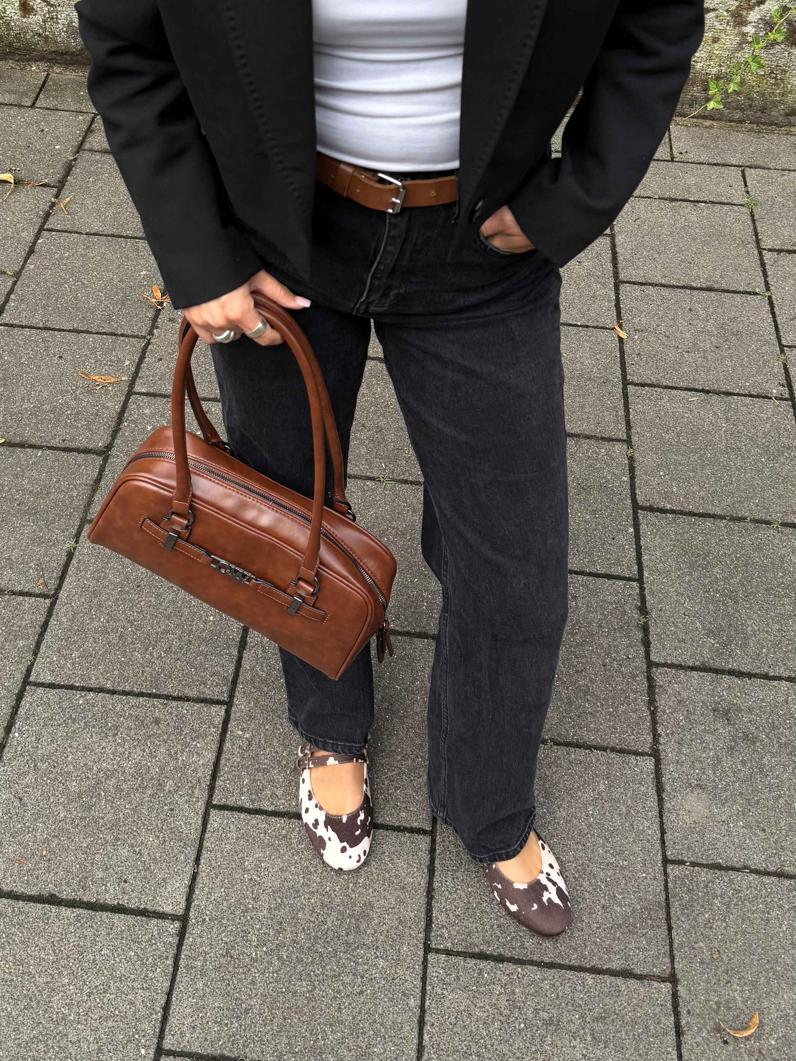 Frau trägt dunkle Jeans, kombiniert mit Cow Print-Flats und brauner East West Bag, Top-Down-Ansicht
