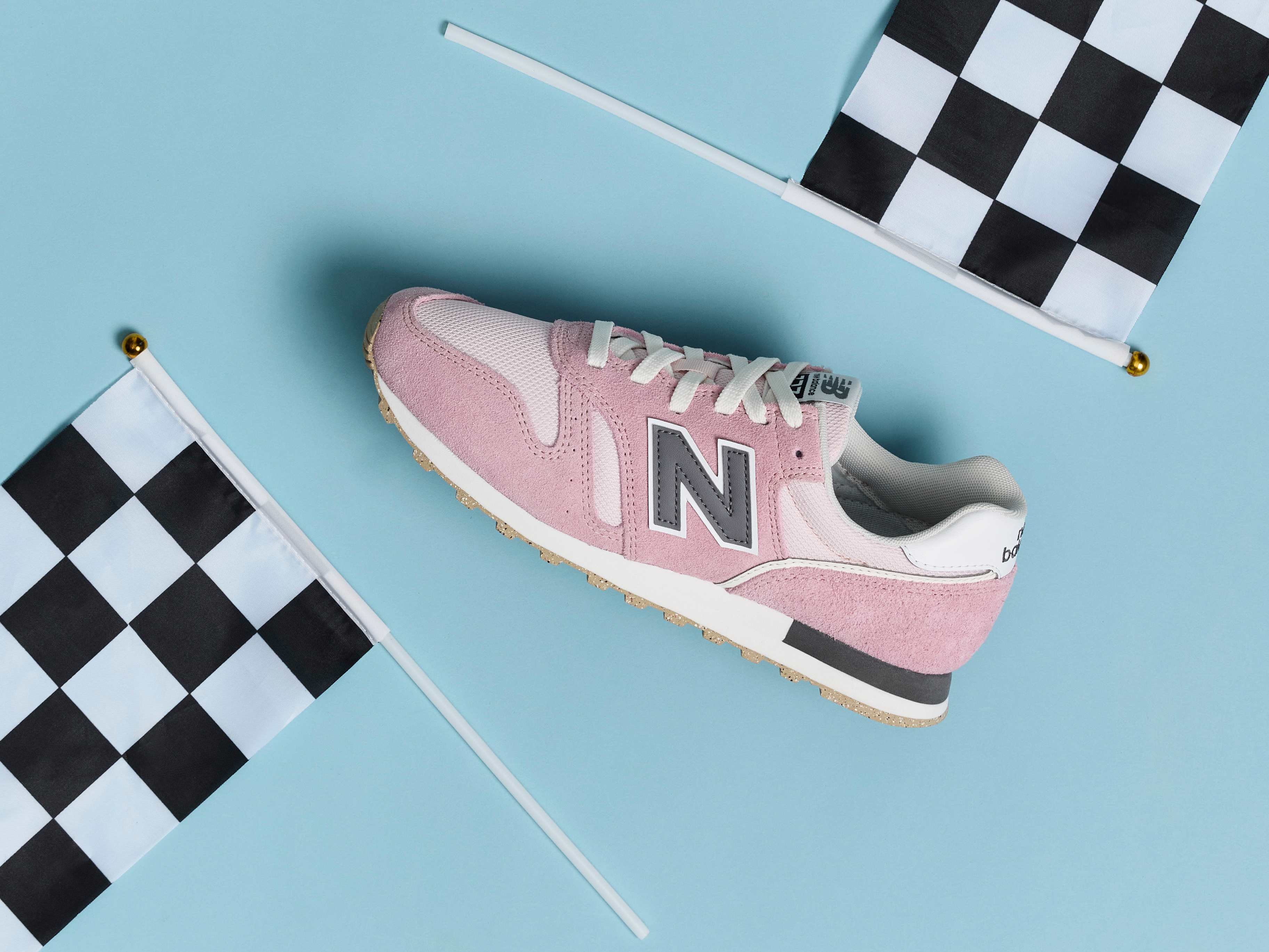 Lachsfarbener Sport-Sneaker liegend neben zwei Flaggen