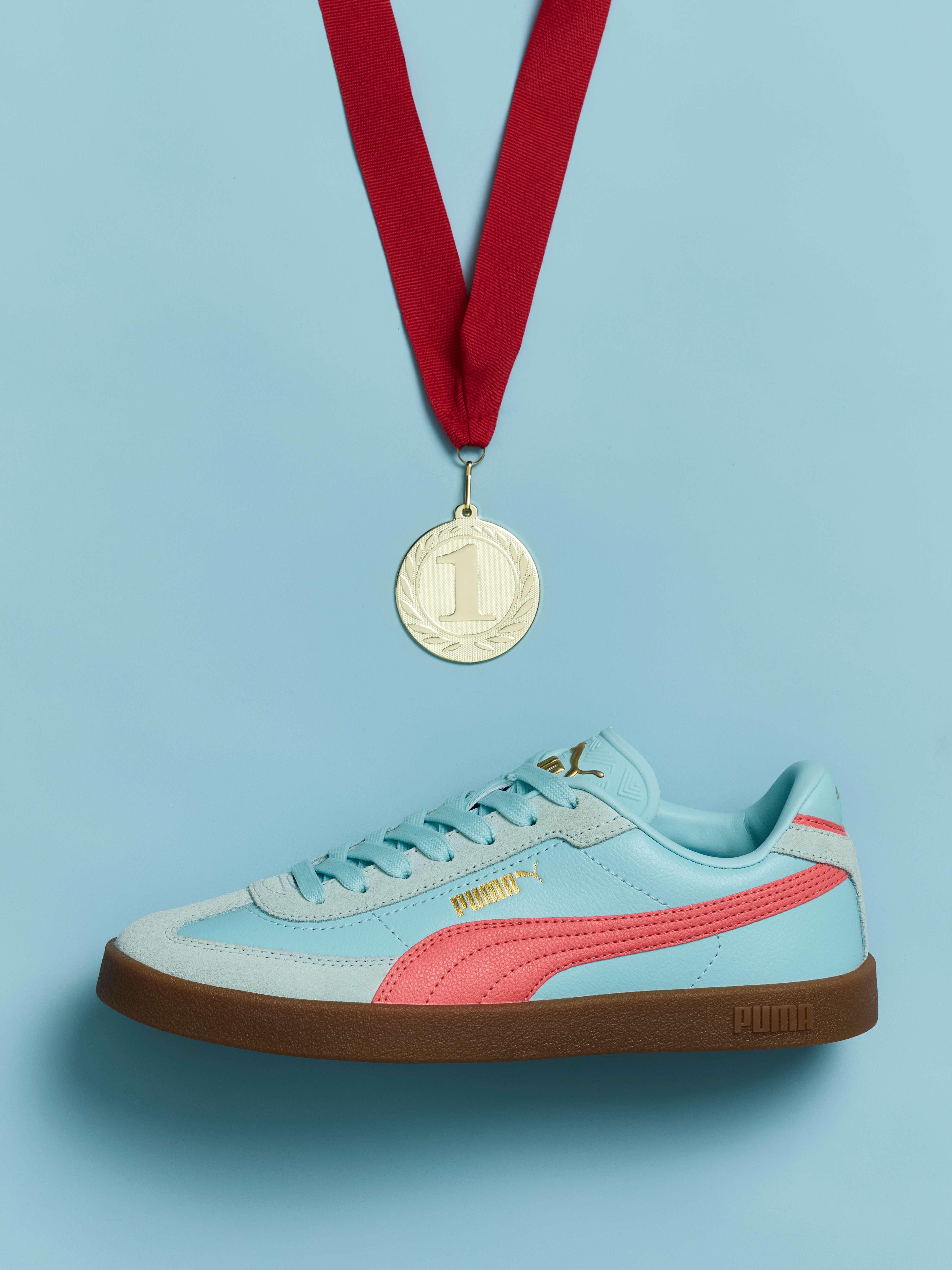 Türkisfarbener Sportsneaker gemeinsam mit Medaille in einer Aufnahme