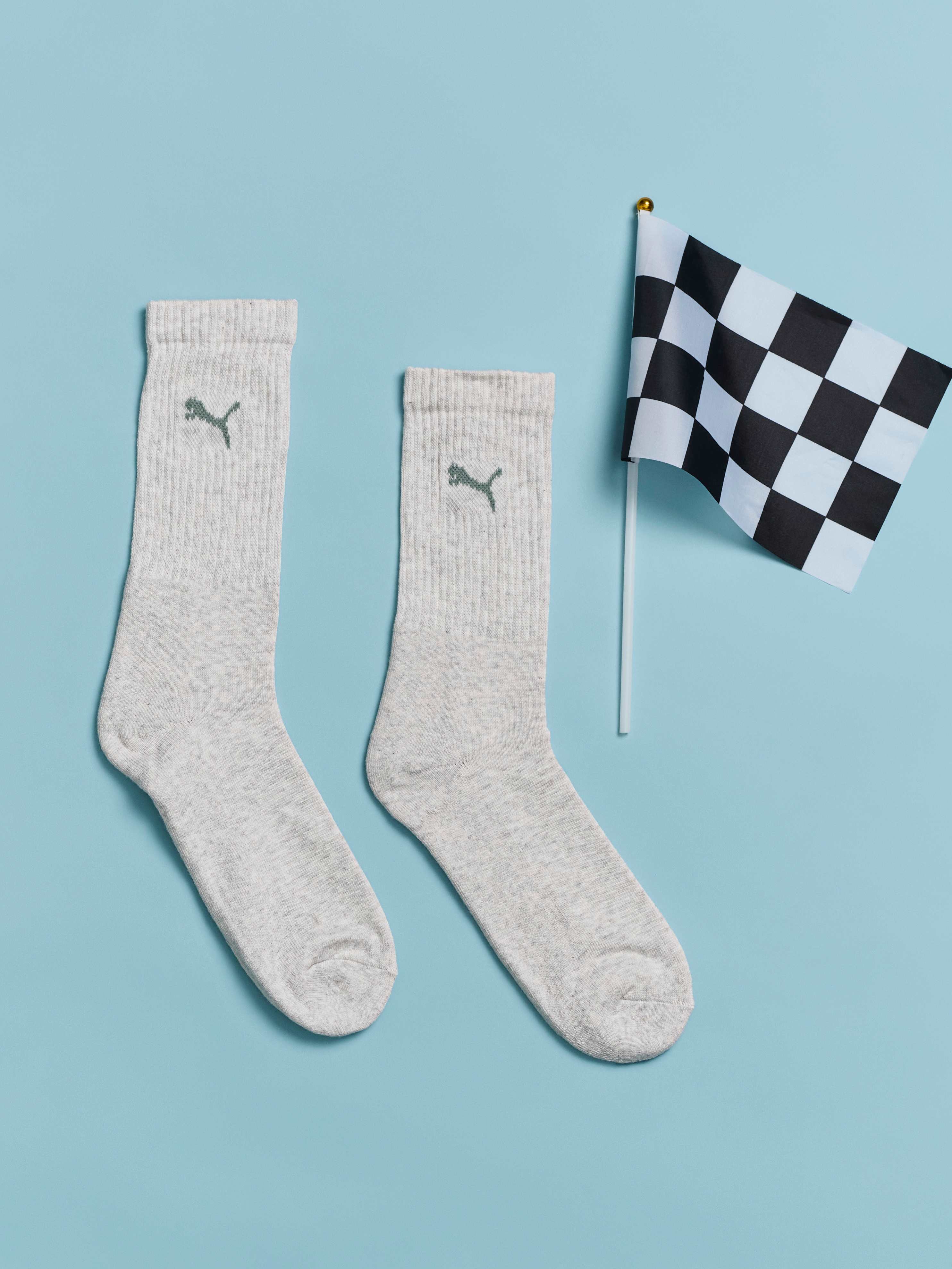 Ein Paar weiße Puma-Sportsocken liegt neben eine Zielflagge