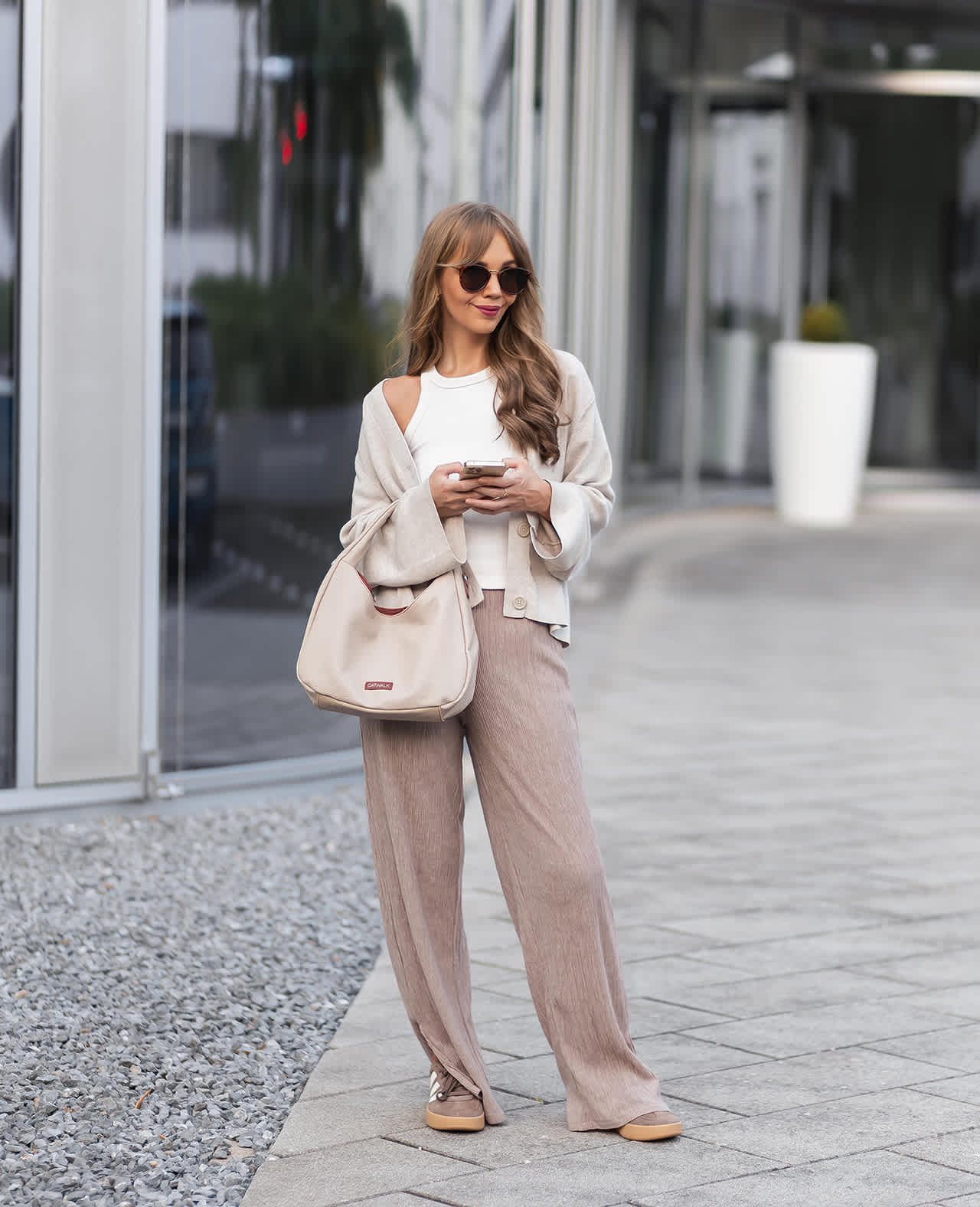 Frau steht in Scandi Style-Look auf Straße, trägt weißes Tank Top mit Cardigan