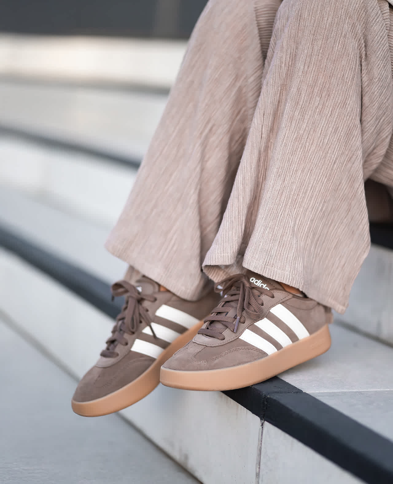 Frau sitzt mit Adidas-Sneakern auf Treppe