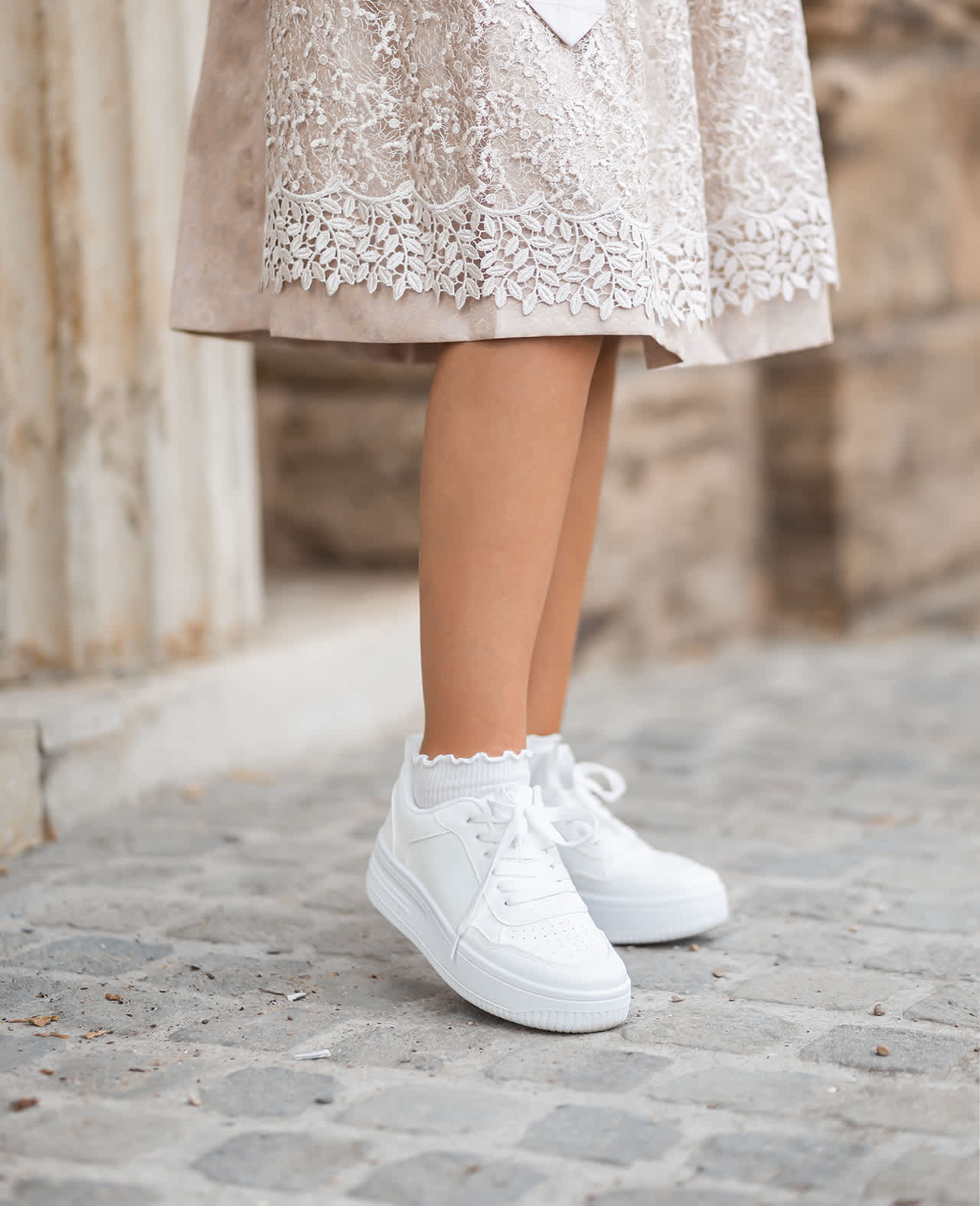 Frau in Spitzen-Dirndl mit weißen Sneaker-Schuhen