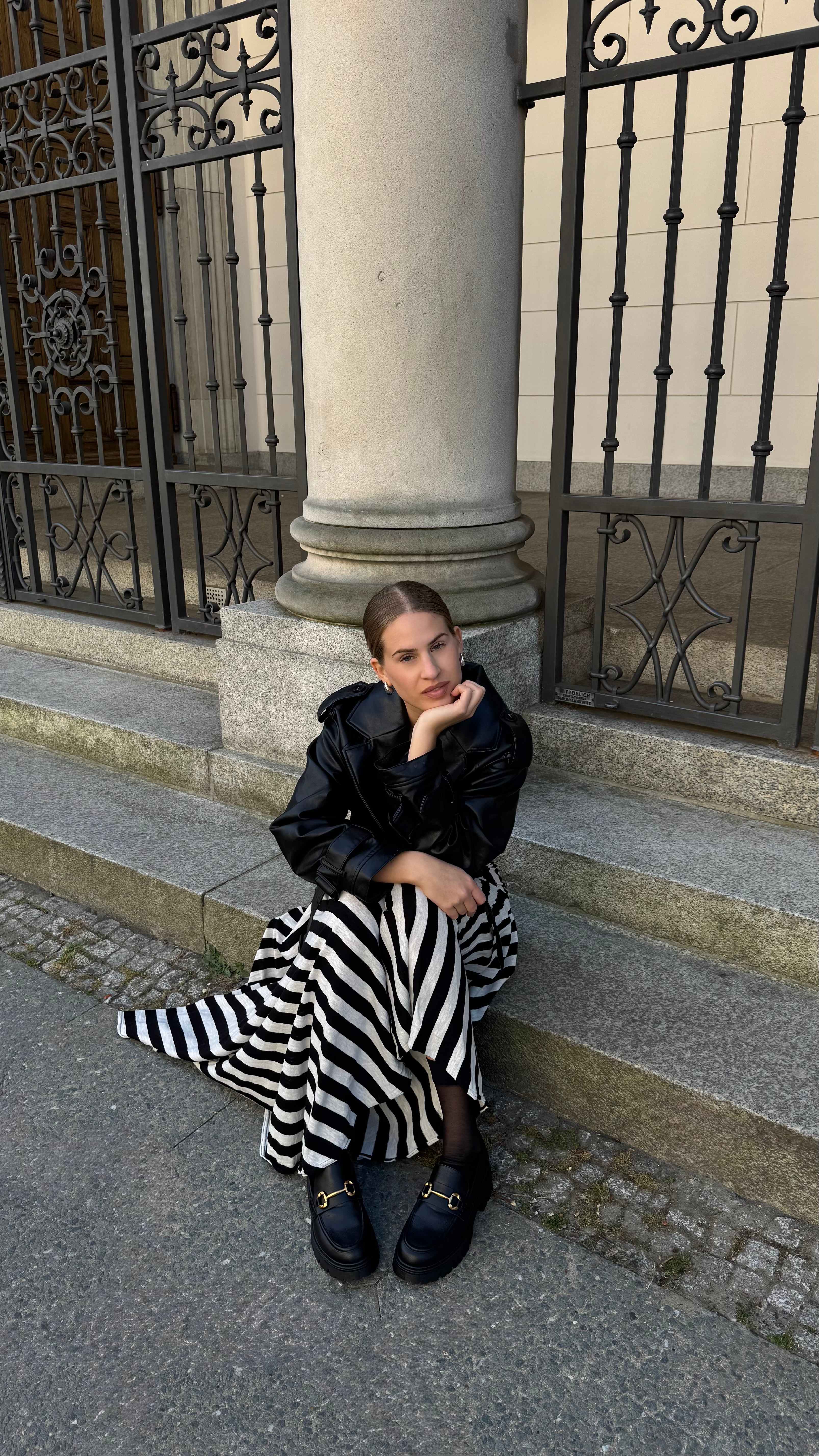 Frau sitzt in herbstlichem Sommerkleid auf Steinstufen