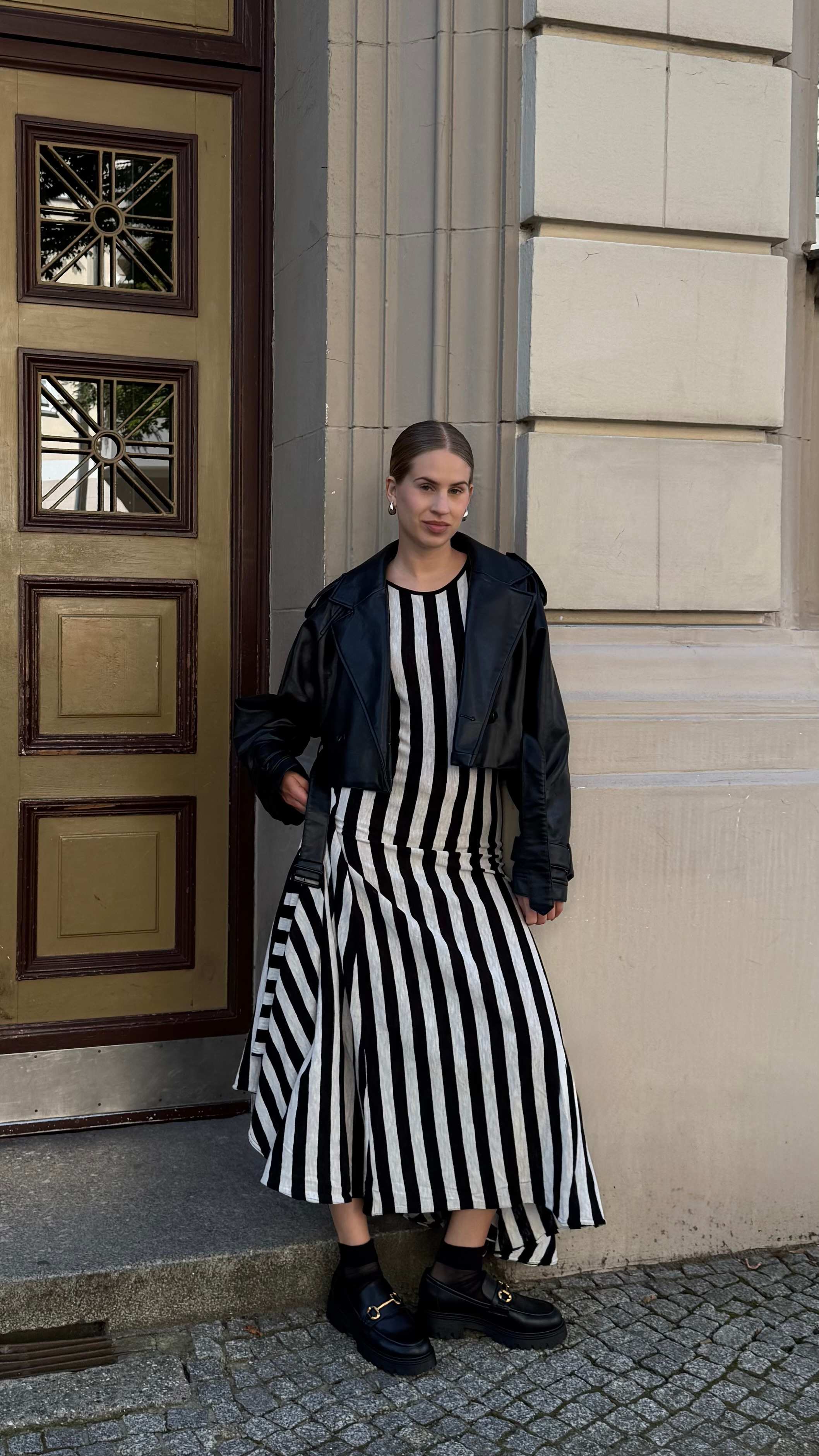 Frau in Zebrastreifen-Kleid steht vor Gebäude