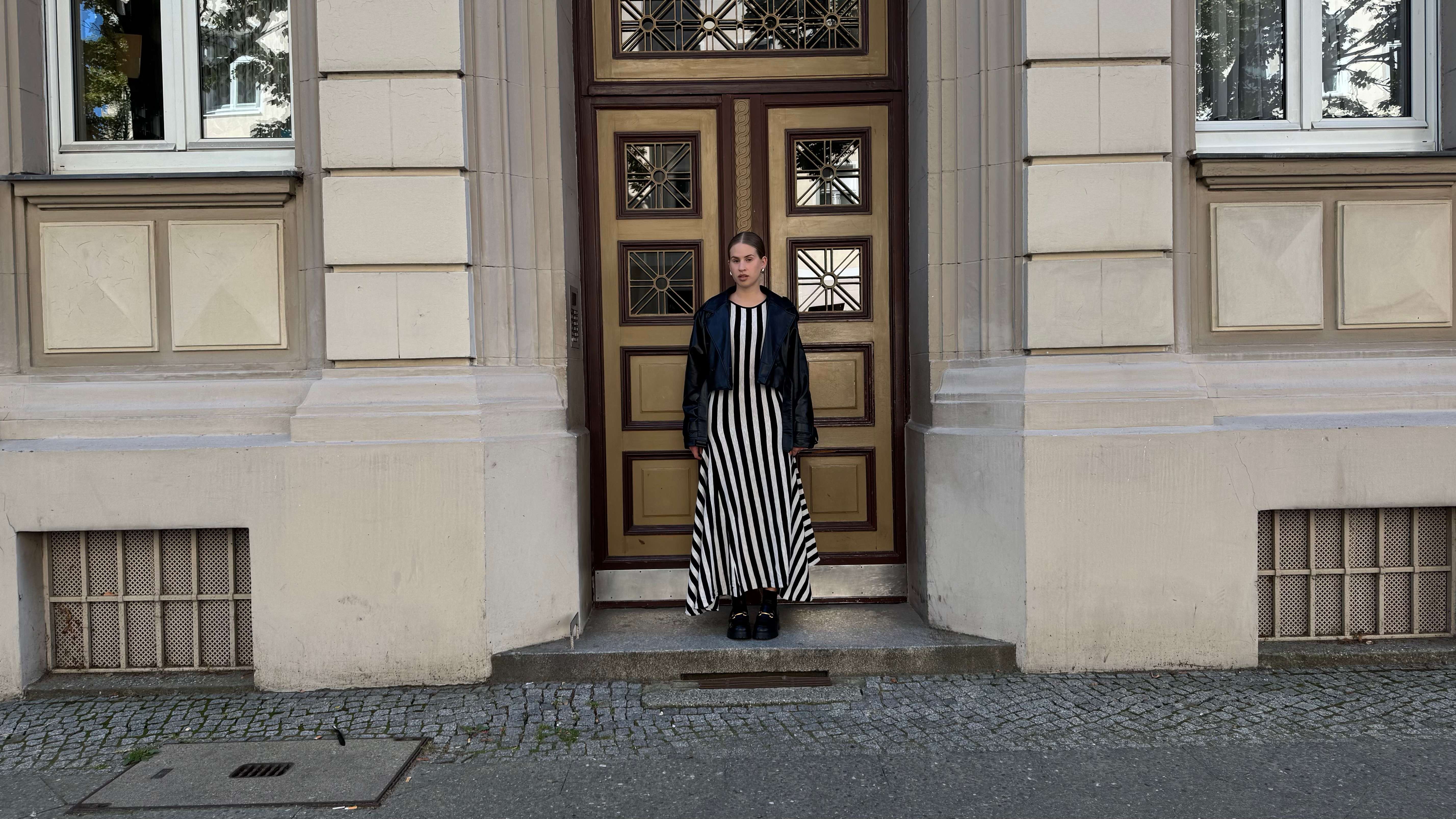 Frau in herbstlichem Kleid im Zebra-Muster steht in Hauseingang