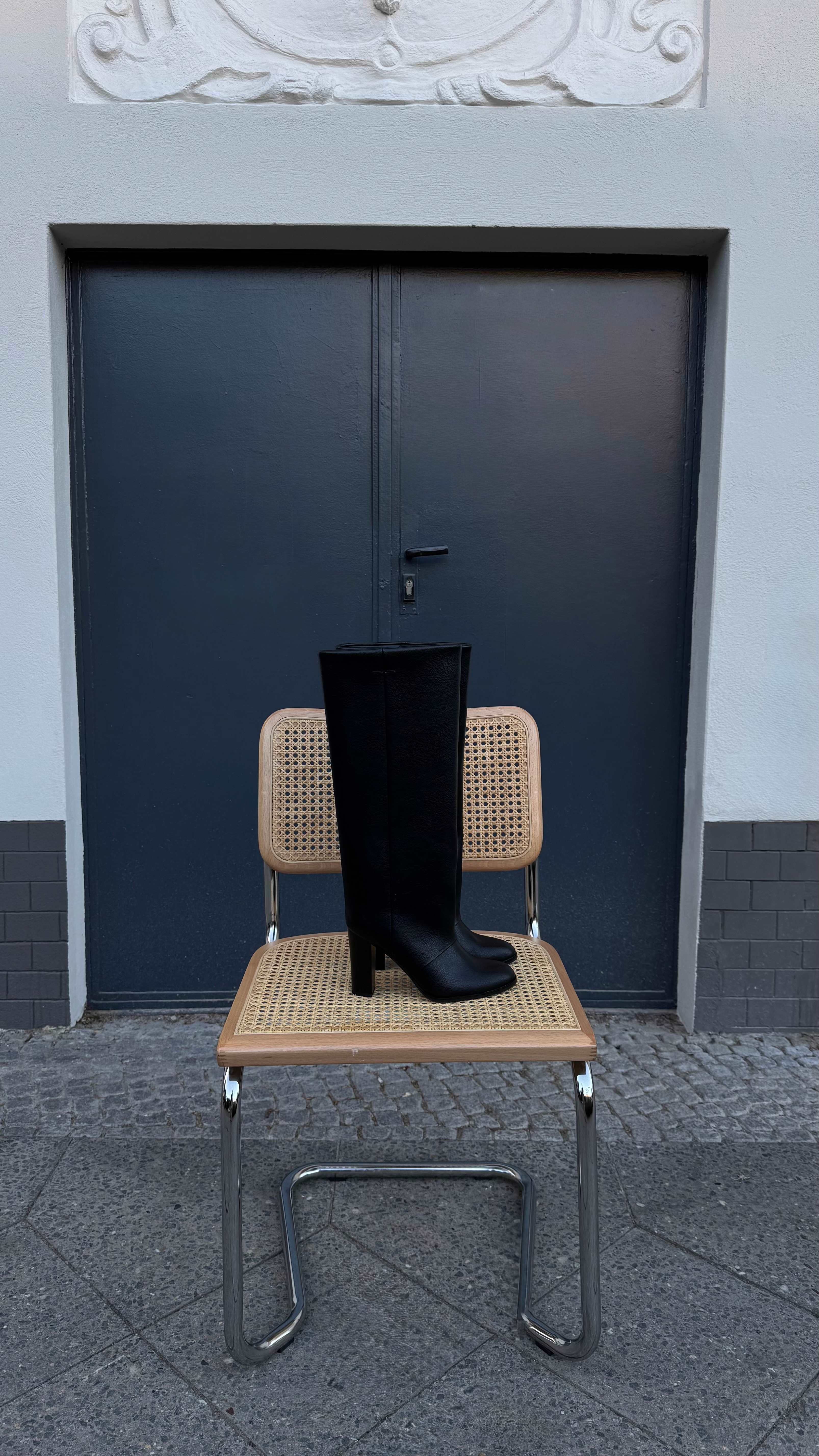 Schwarzer Underknee Boot steht auf einem Stuhl