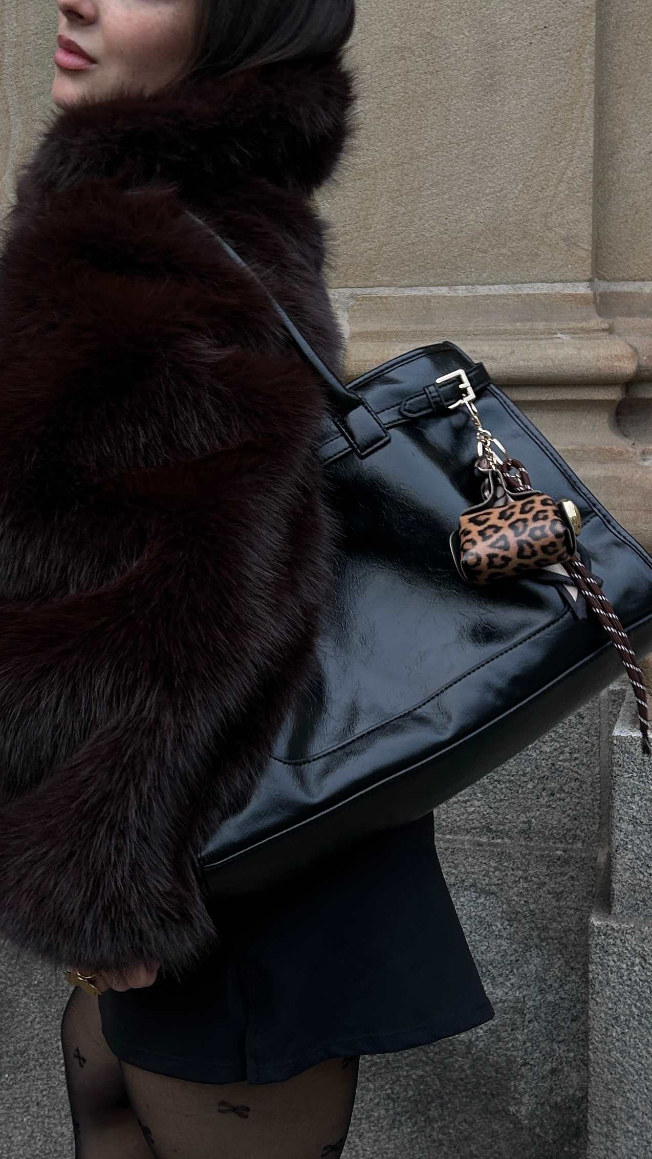 Frau trägt schwarze Kunstfell-Jacke mit passender Handtasche in Leder-Optik