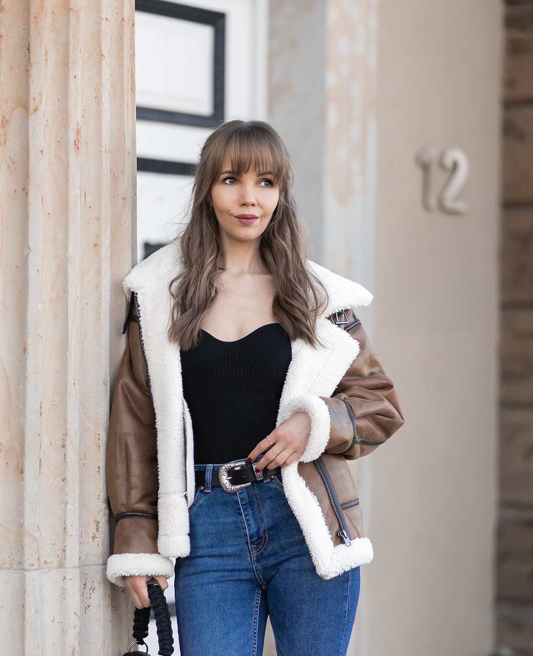 Frau in einem dem Älskling-Trend nachempfundenen Outfit lehnt an Steinsäule