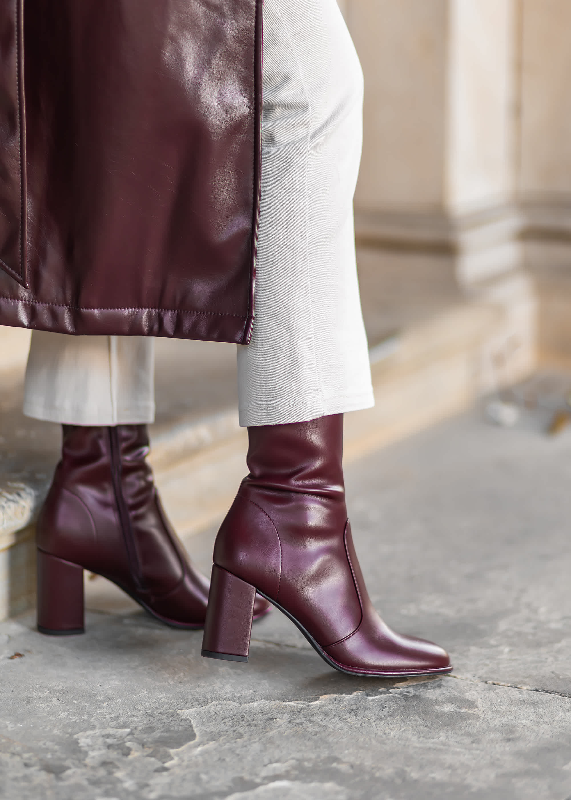 Close-Up einer Frau, die burgunderfarbene Stiefeletten trägt