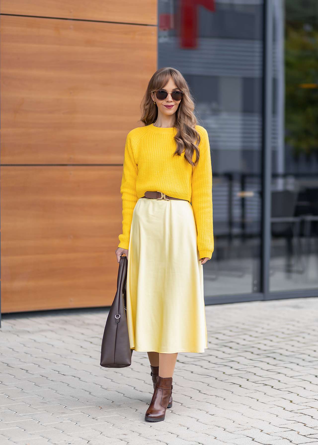 Frau in knallgelbem Outfit, mit hellgelbem Pullover und blassgelbem Slip Skirt