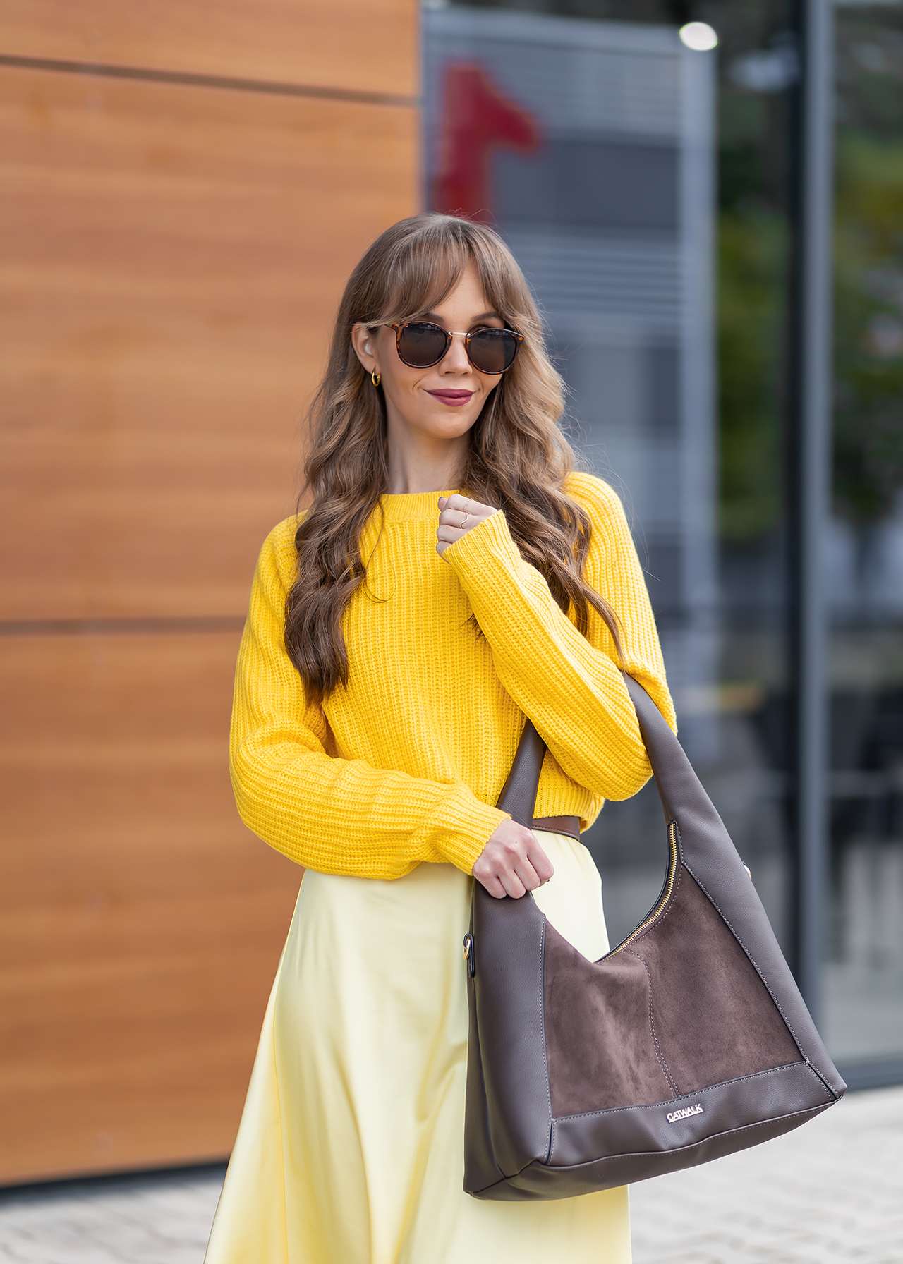 Frau trägt Strickpullover in Butter Yellow, kombiniert mit brauner Handtasche