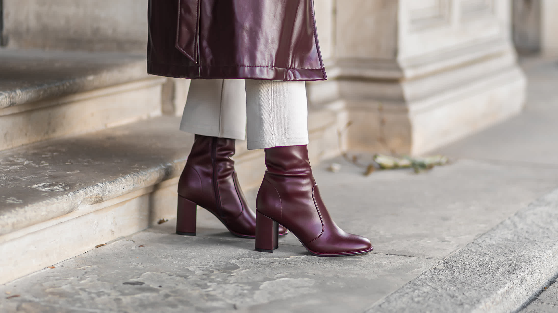 Close-Up einer Frau in burgunderfarbenen Stiefeletten, stehend auf Treppenstufen