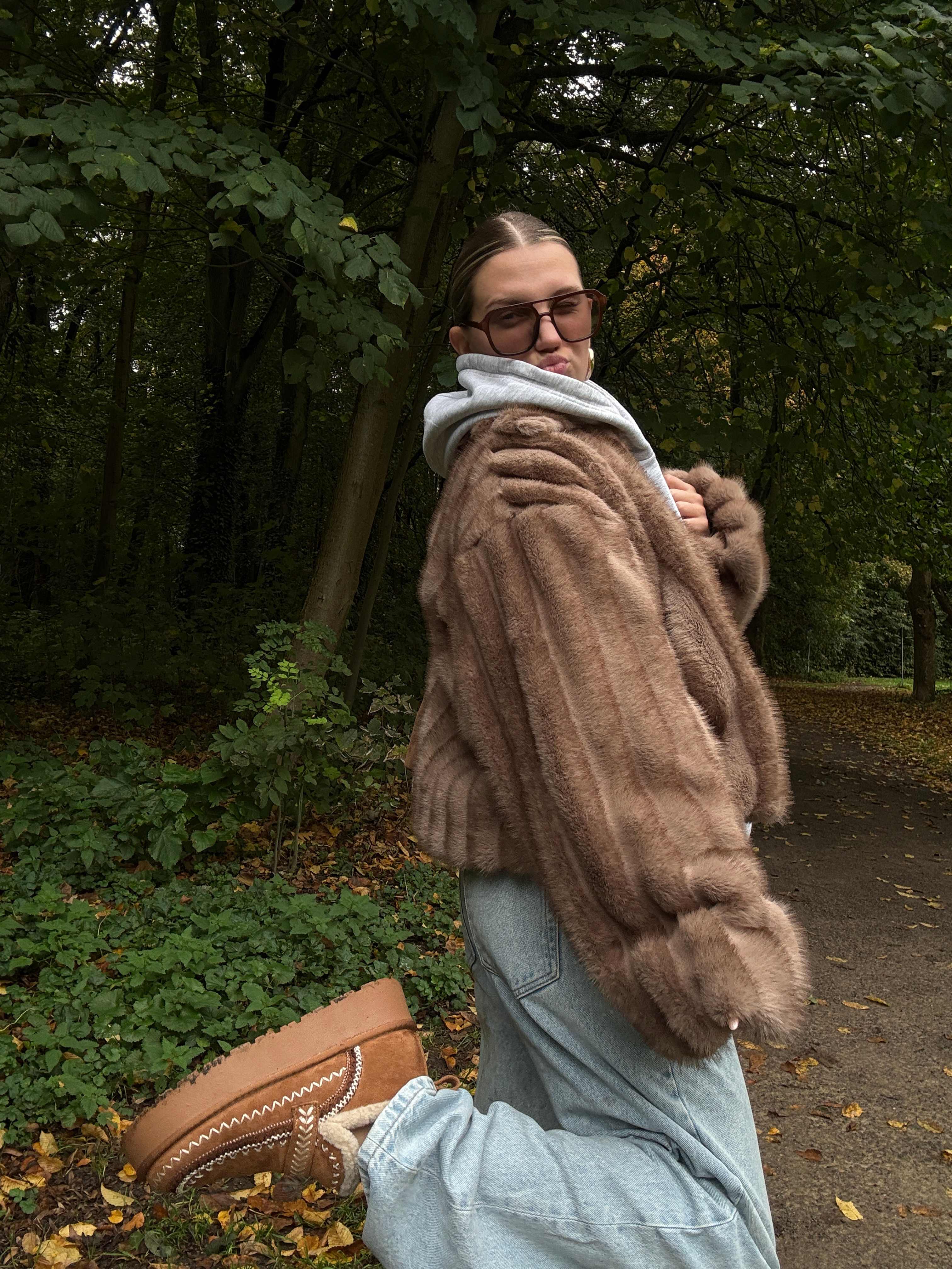 Frau posiert in flauschigem Outfit in Parkanlage