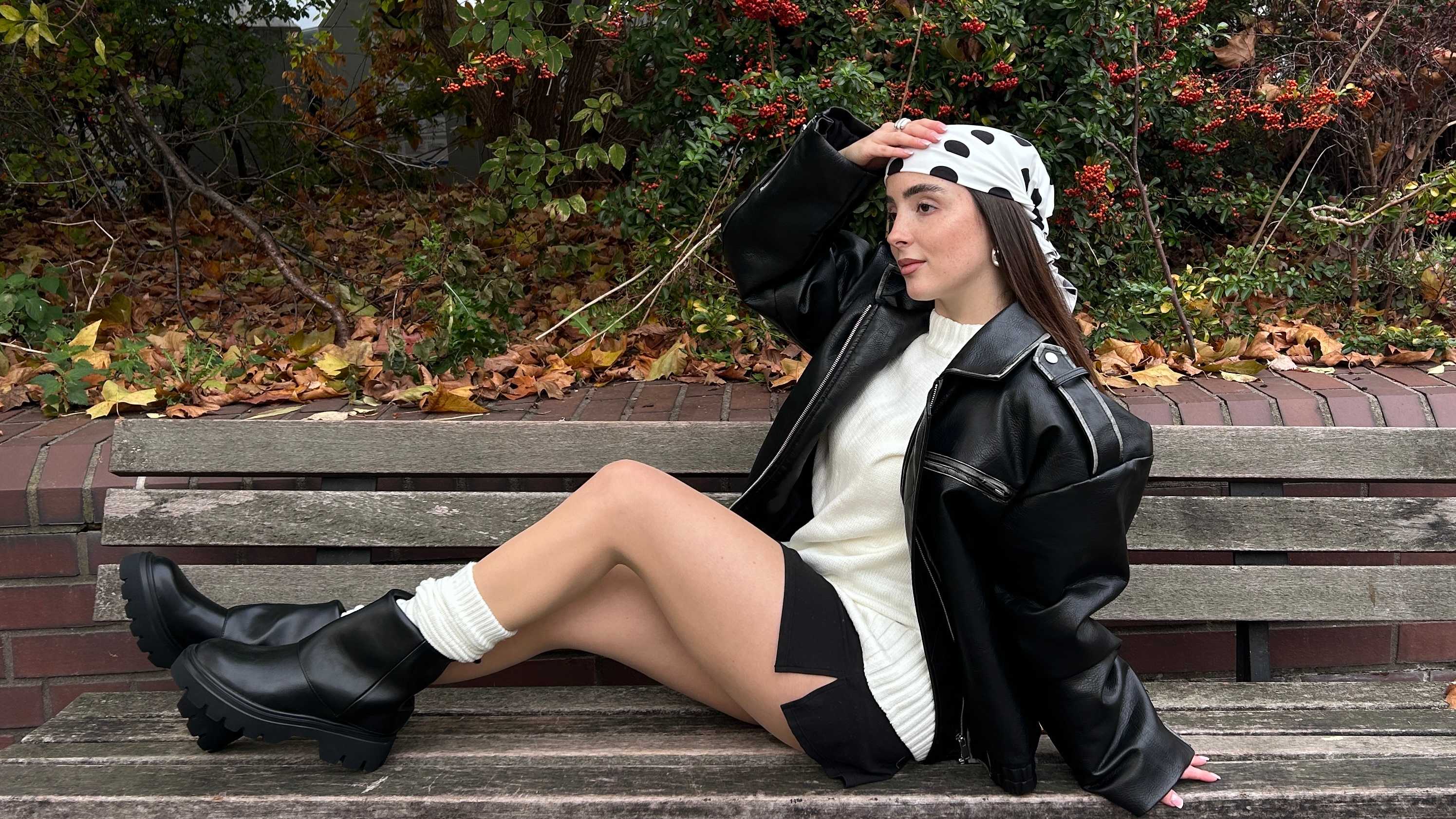 Frau mit schwarzer Jacke, weißem Shirt und Umschlag-Boots, sitzt auf Holzbank