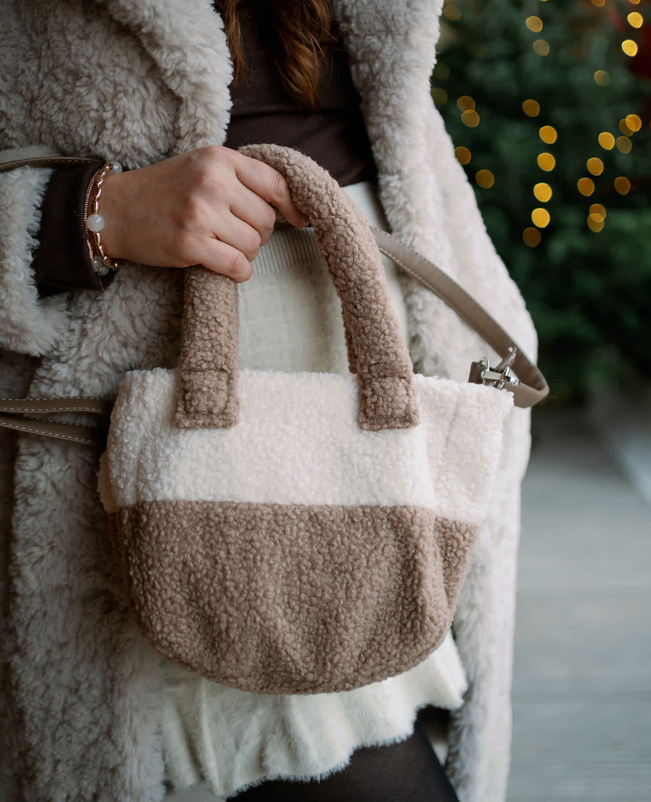Frau hält weiß-braun gestreifte Handtasche in Plüschoptik in der Hand
