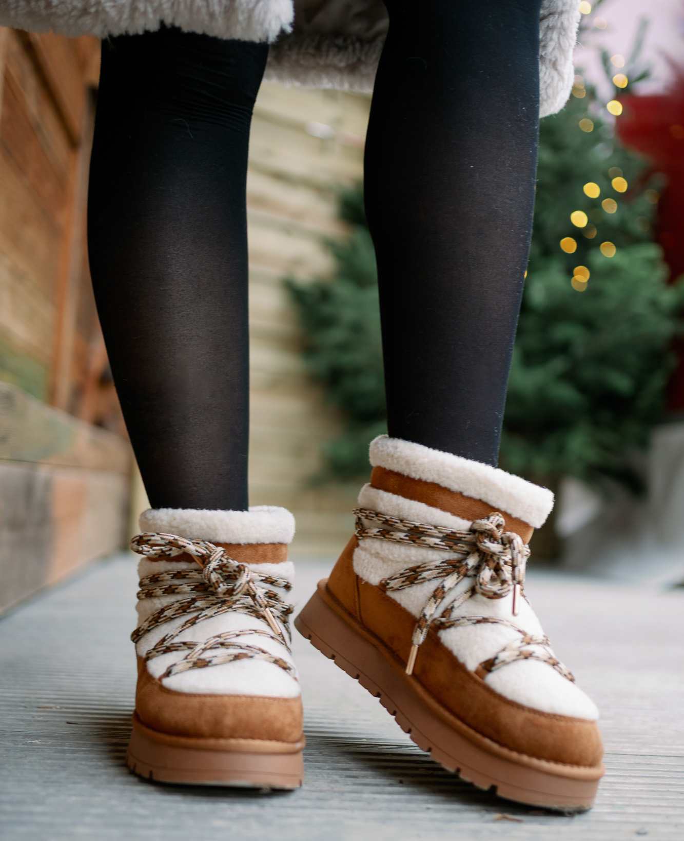 Nahaufnahme einer Frau, die braun-weiße Boots mit Kuschelfell trägt