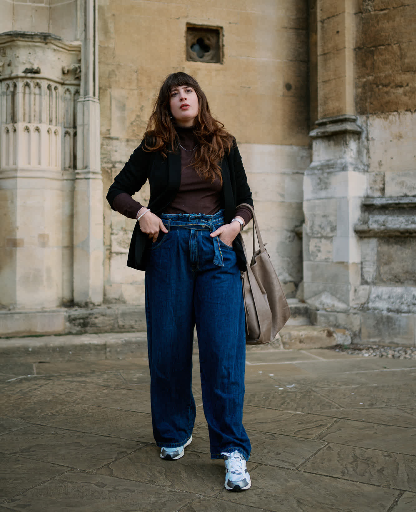 Frau trägt tiefblaue Paperbag-Jeans, kombiniert mit Rollkragen-Pullover und Sneakern, für den Normcore Style