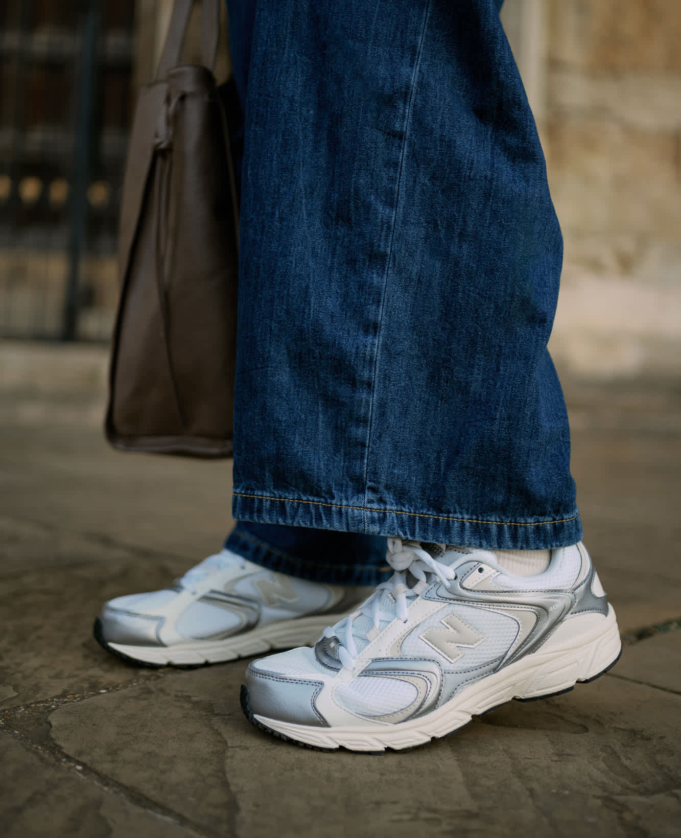 Frau trägt weiße Sneaker-Schuhe, kombiniert mit blauer Jeans-Hose
