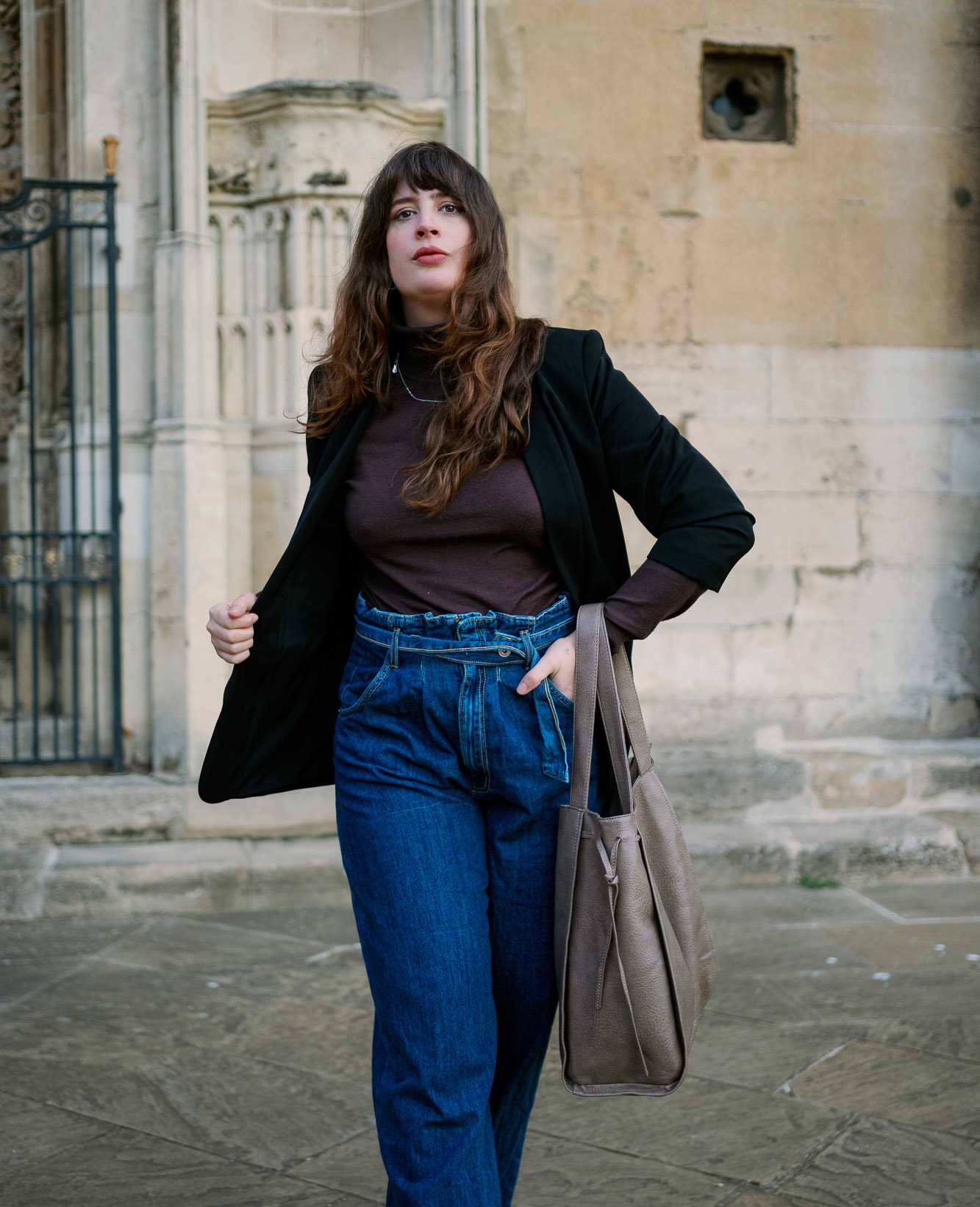 Frau in schwarzem Blazer und Top, kombiniert mit blauer Jeanshose