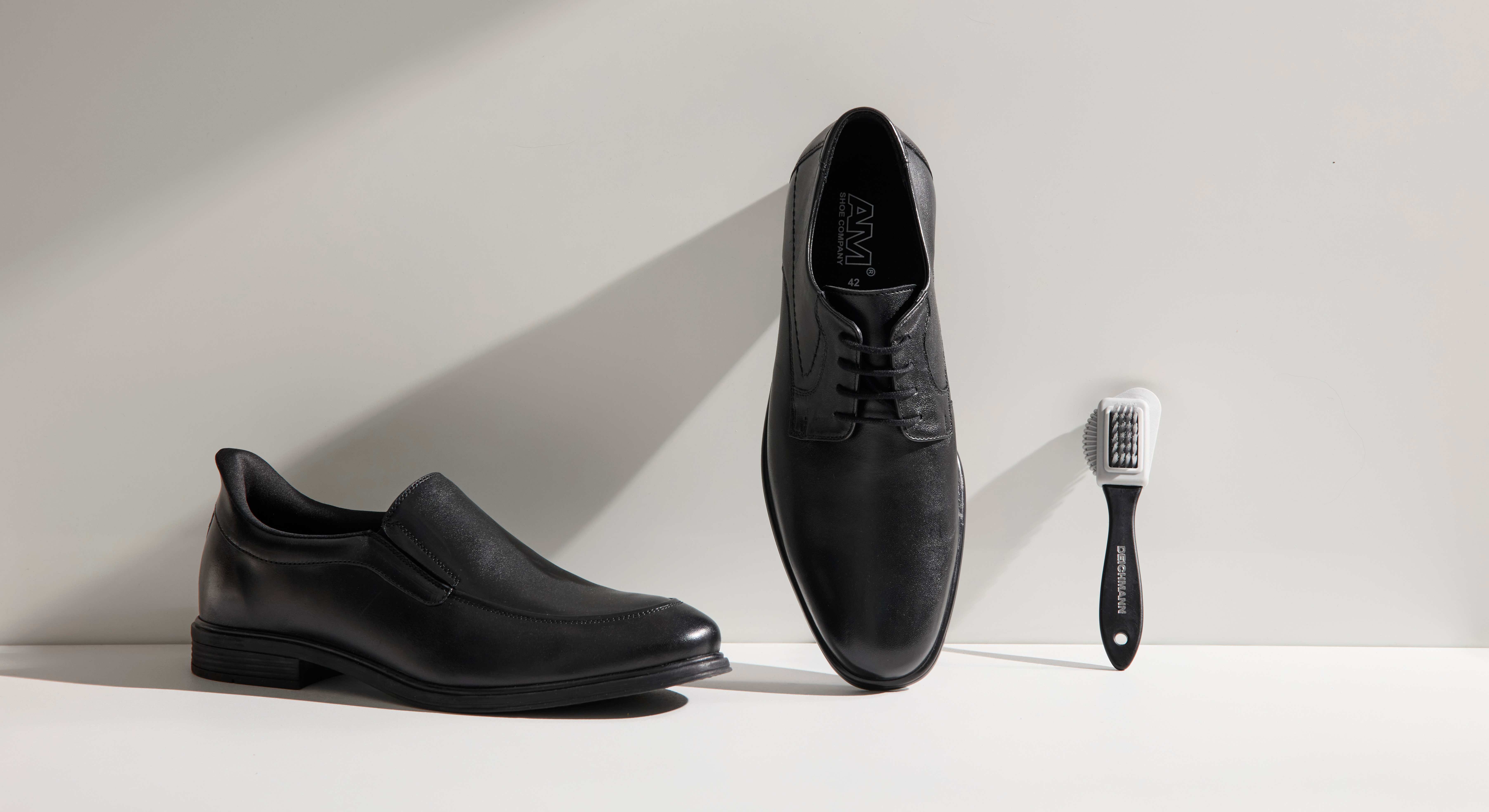Schwarze Lederschuhe stehen neben einer Lederbürste zum Reinigen
