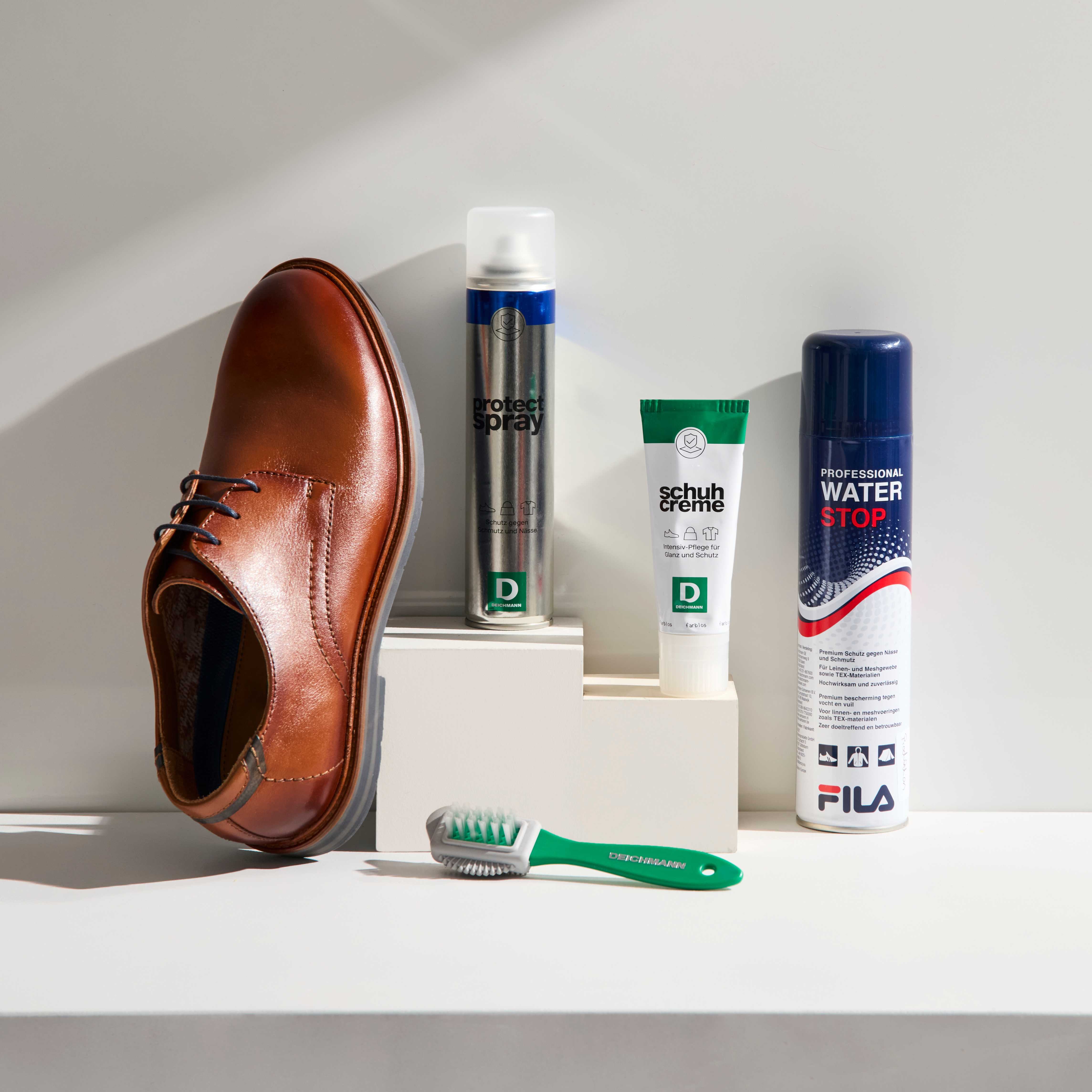 Brauner Lederschuhe lehnt neben mehreren Deichmann-Pflegeprodukten