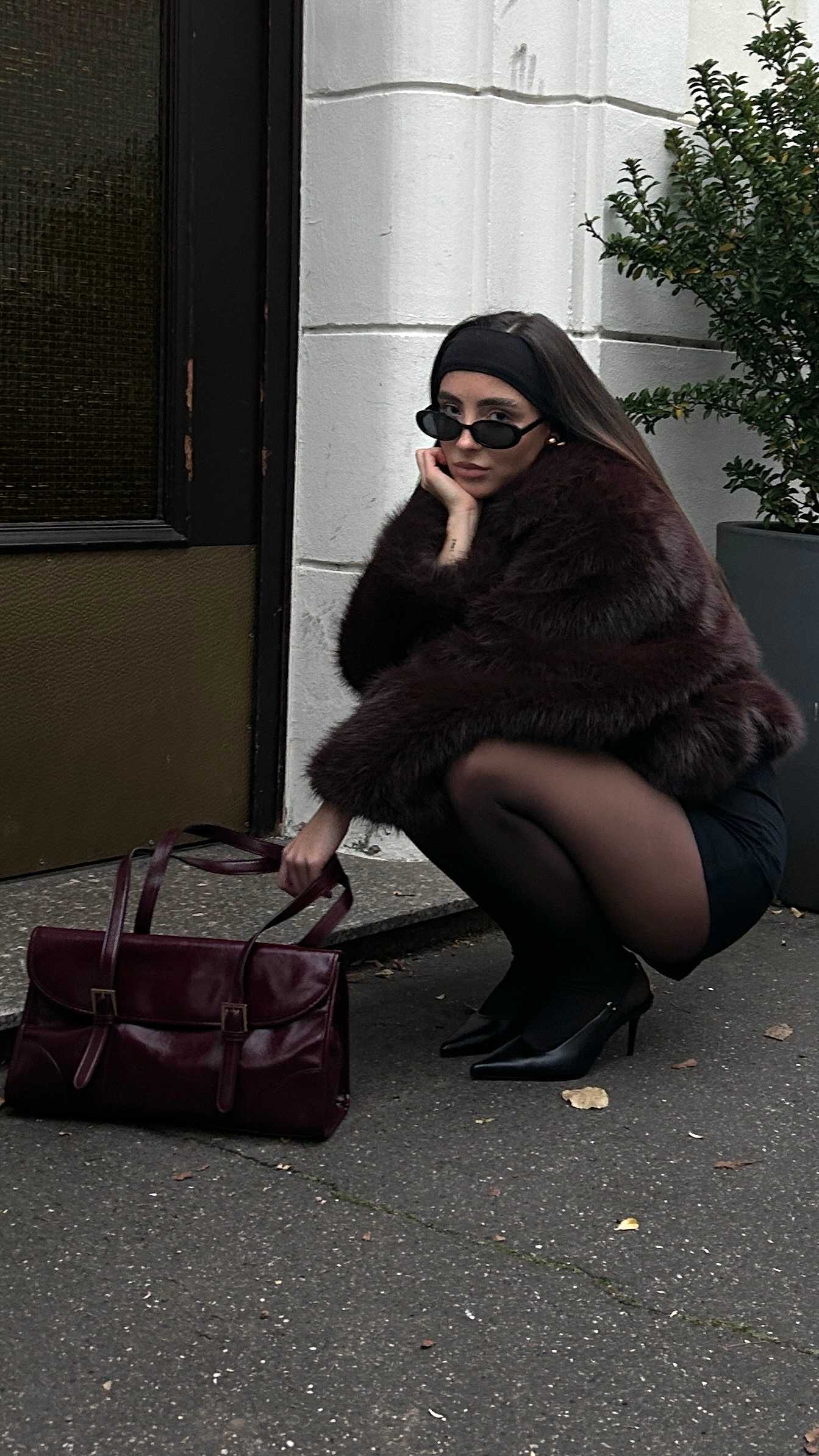 Frau in Mob Wife-Look, mit Felljacke, in kniender Position